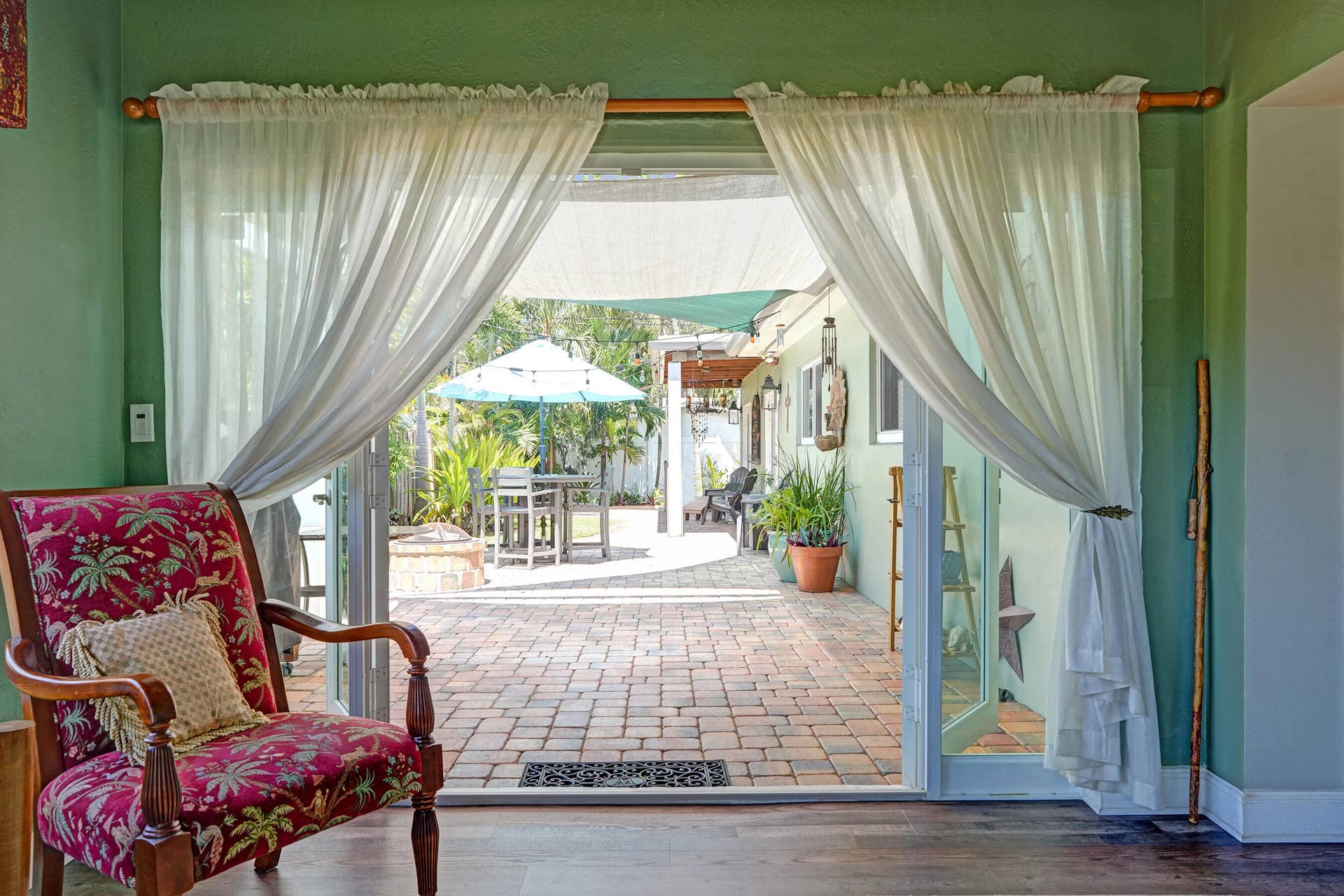 Bright Florida room featuring exposed wood beams, tongue-and-groove ceiling, French doors, and seamless indoor-outdoor living. This room has that special Charm!