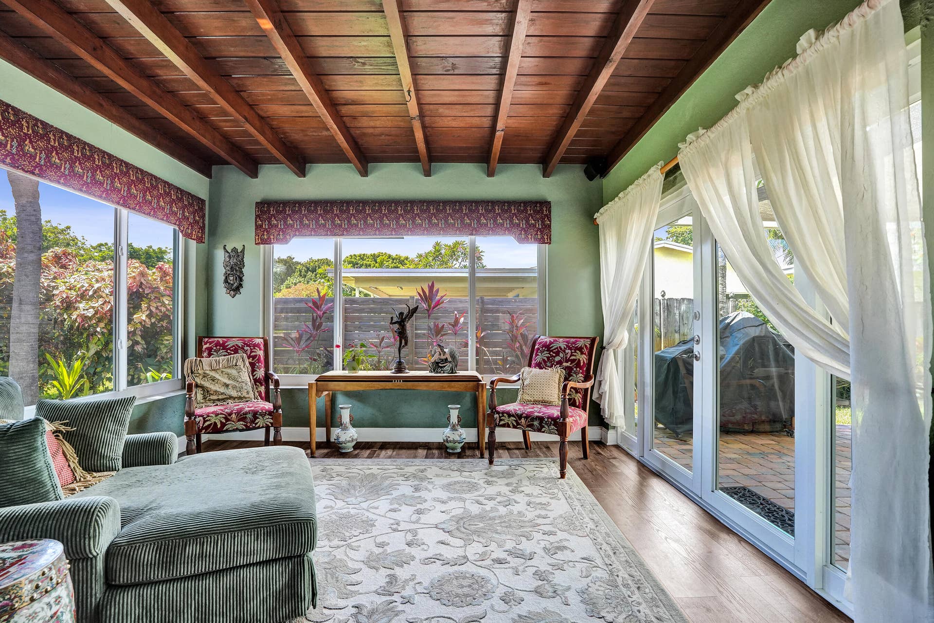 Bright Florida room featuring exposed wood beams, tongue-and-groove ceiling, French doors, and seamless indoor-outdoor living. This room has that special Charm!