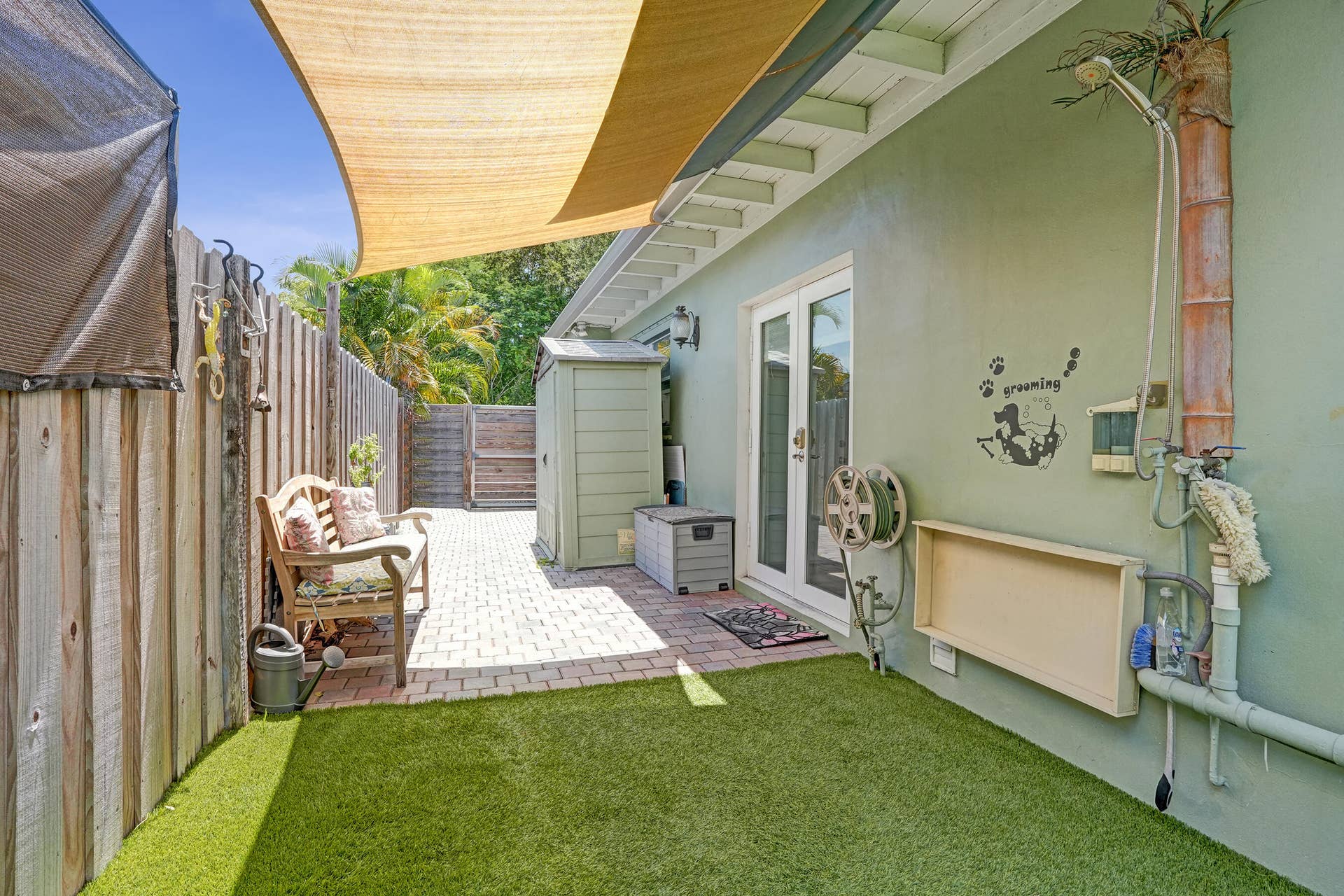 Private side yard featuring pet-friendly turf and a convenient outdoor wash stationperfect for rinsing off pets, kids, or after gardening.