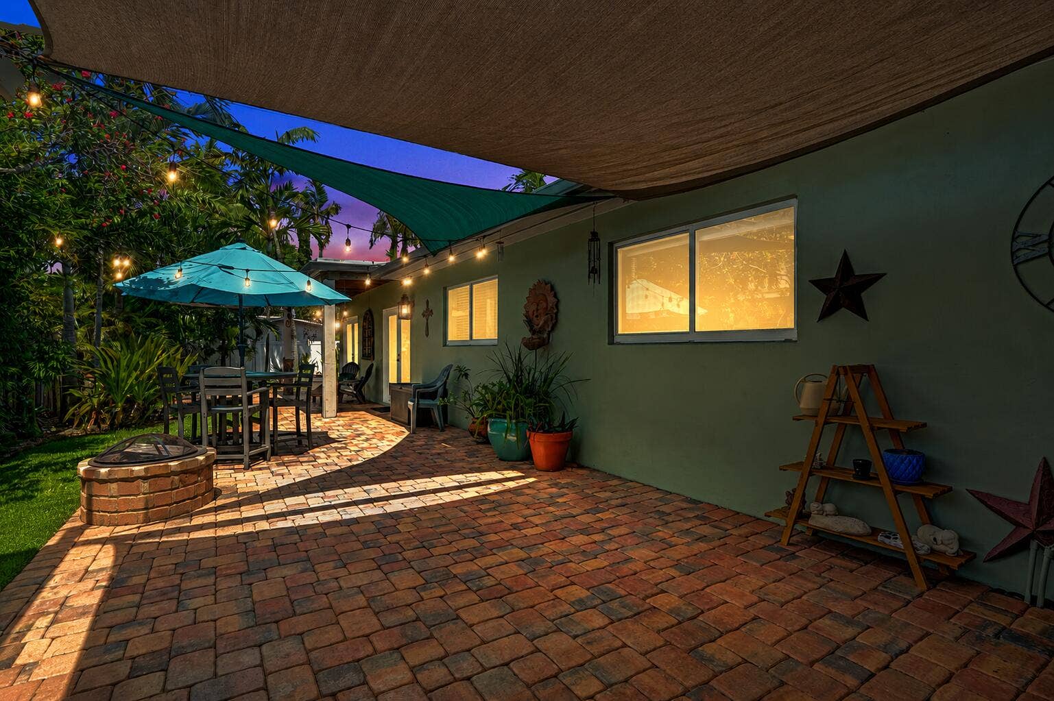 Authentic New Orleans copper gas coach lanterns, brick paver patio, lush tropical landscaping, and a true resort-style outdoor retreat.