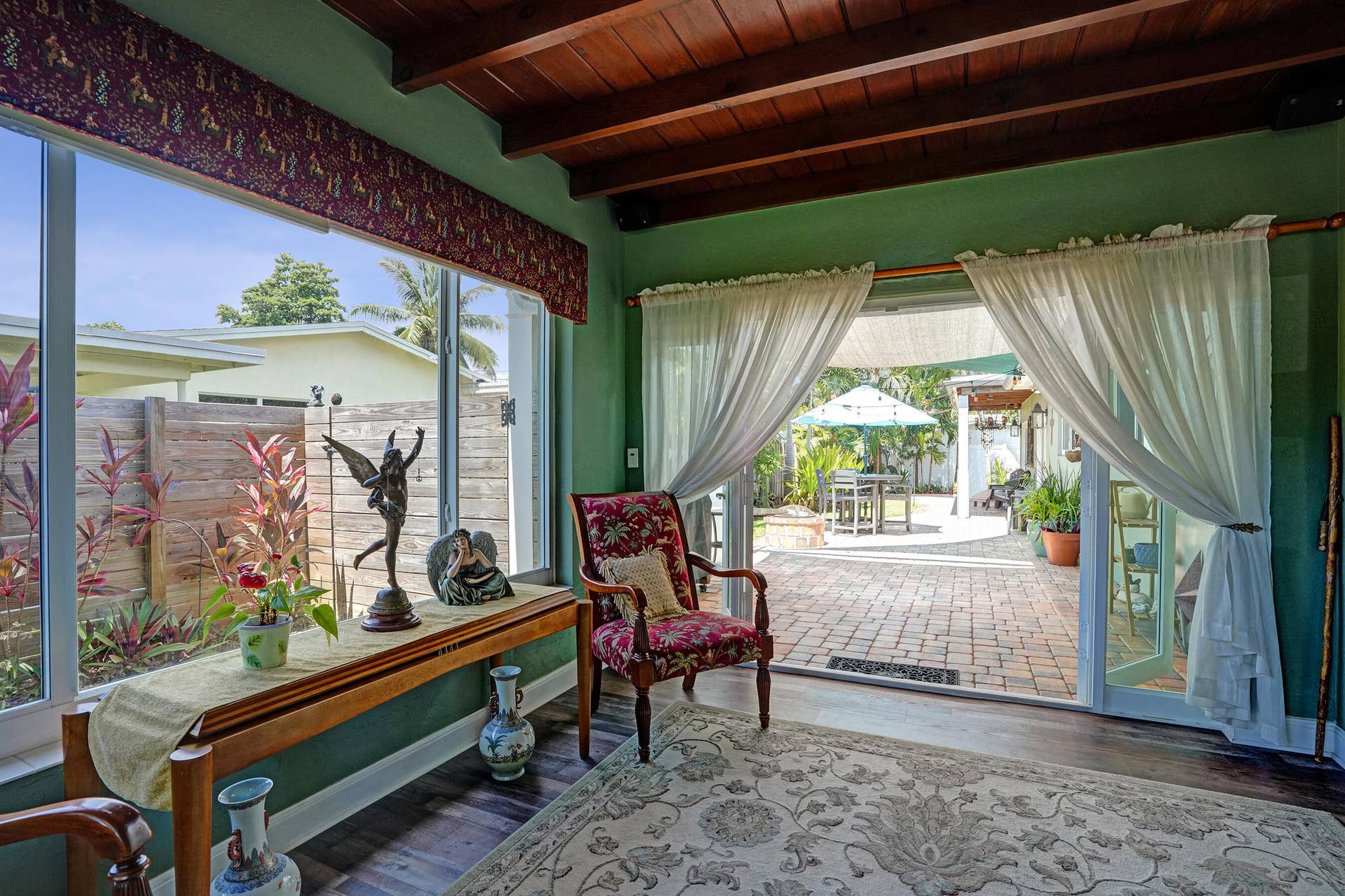 Bright Florida room featuring exposed wood beams, tongue-and-groove ceiling, French doors, and seamless indoor-outdoor living. This room has that special Charm!