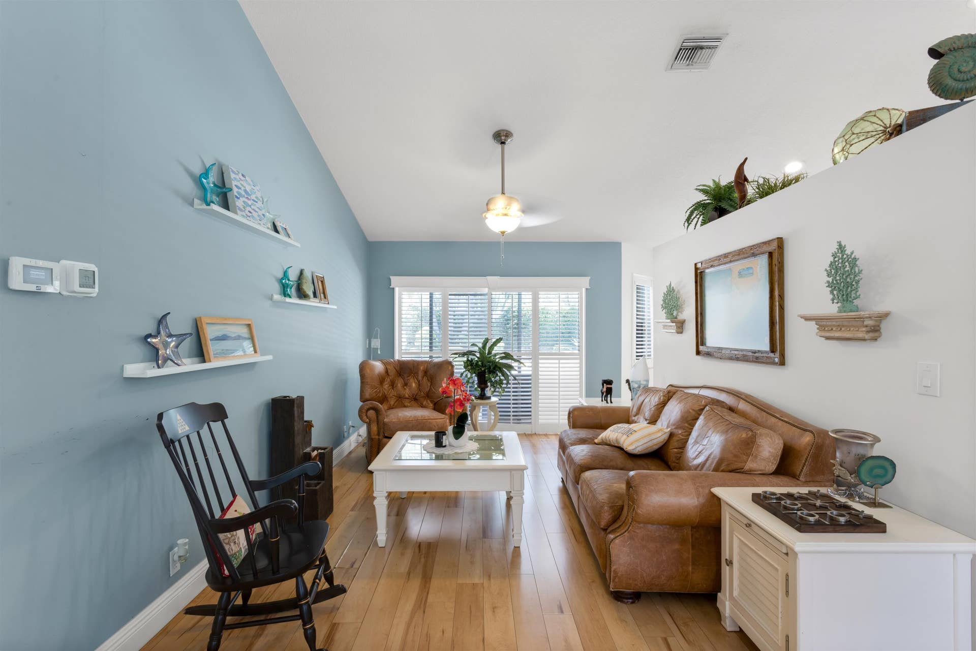 Front living area with vaulted ceilings, plantation shutters leading to backyard