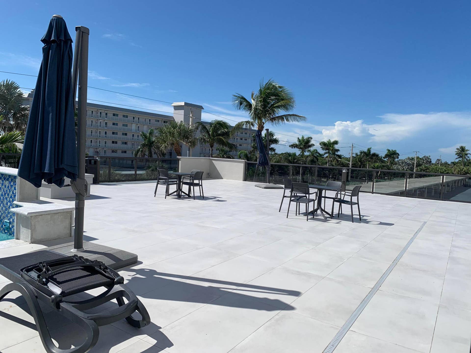 3115 S Ocean Boulevard, #1002, Highland Beach, FL 33487 Spacious outdoor terrace featuring large format light-colored paving, a glass railing system, and integrated channel drains