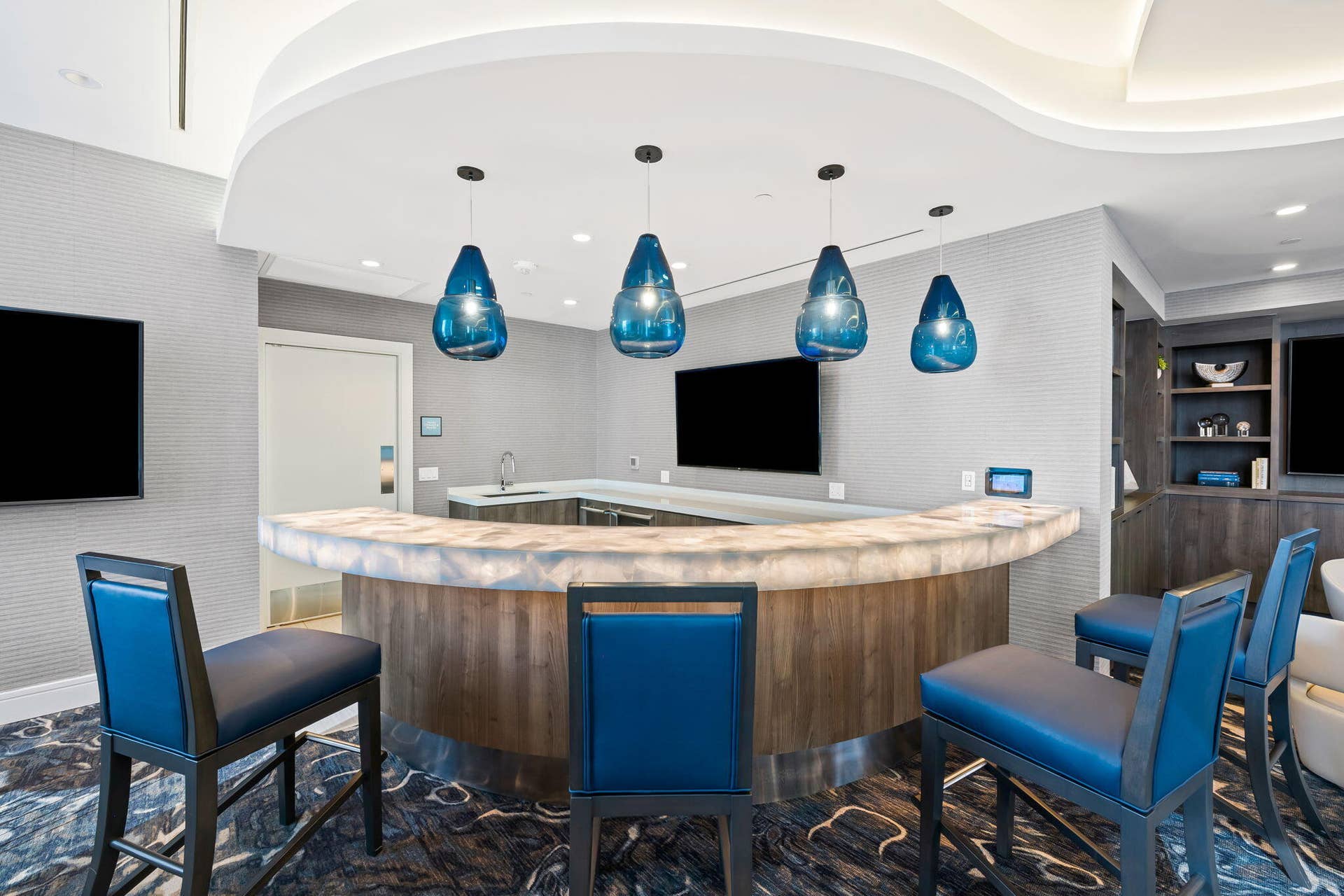 100 E Las Olas Boulevard, #3804, Fort Lauderdale, FL 33301 Curved bar featuring a translucent countertop, wood-finish paneling, and a stainless steel kickplate