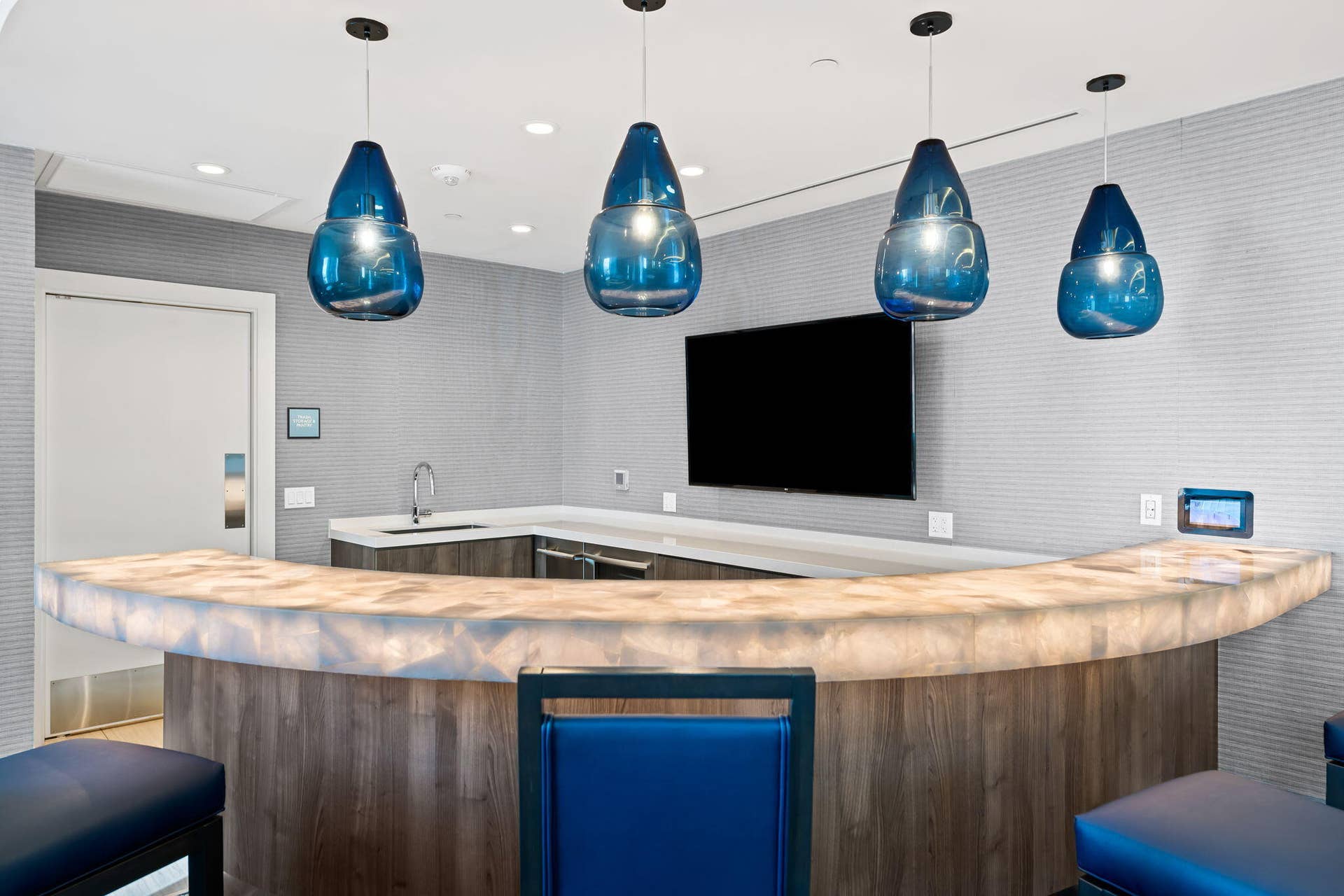 100 E Las Olas Boulevard, #3804, Fort Lauderdale, FL 33301 Curved bar with a translucent countertop and wood-finish paneling