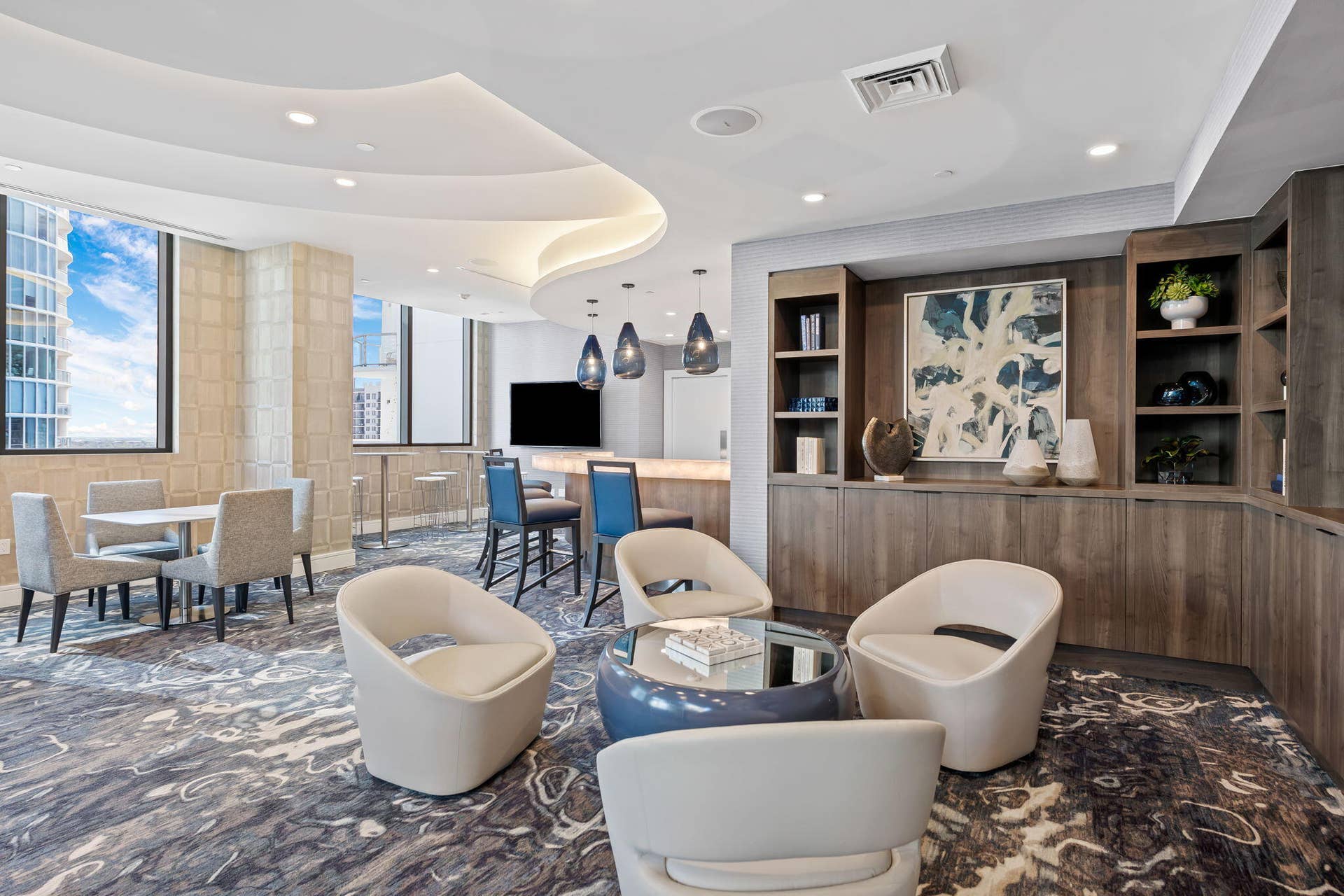 100 E Las Olas Boulevard, #3804, Fort Lauderdale, FL 33301 Elegant communal space featuring a built-in bar, wood-finish cabinetry with integrated shelving, and a patterned carpet
