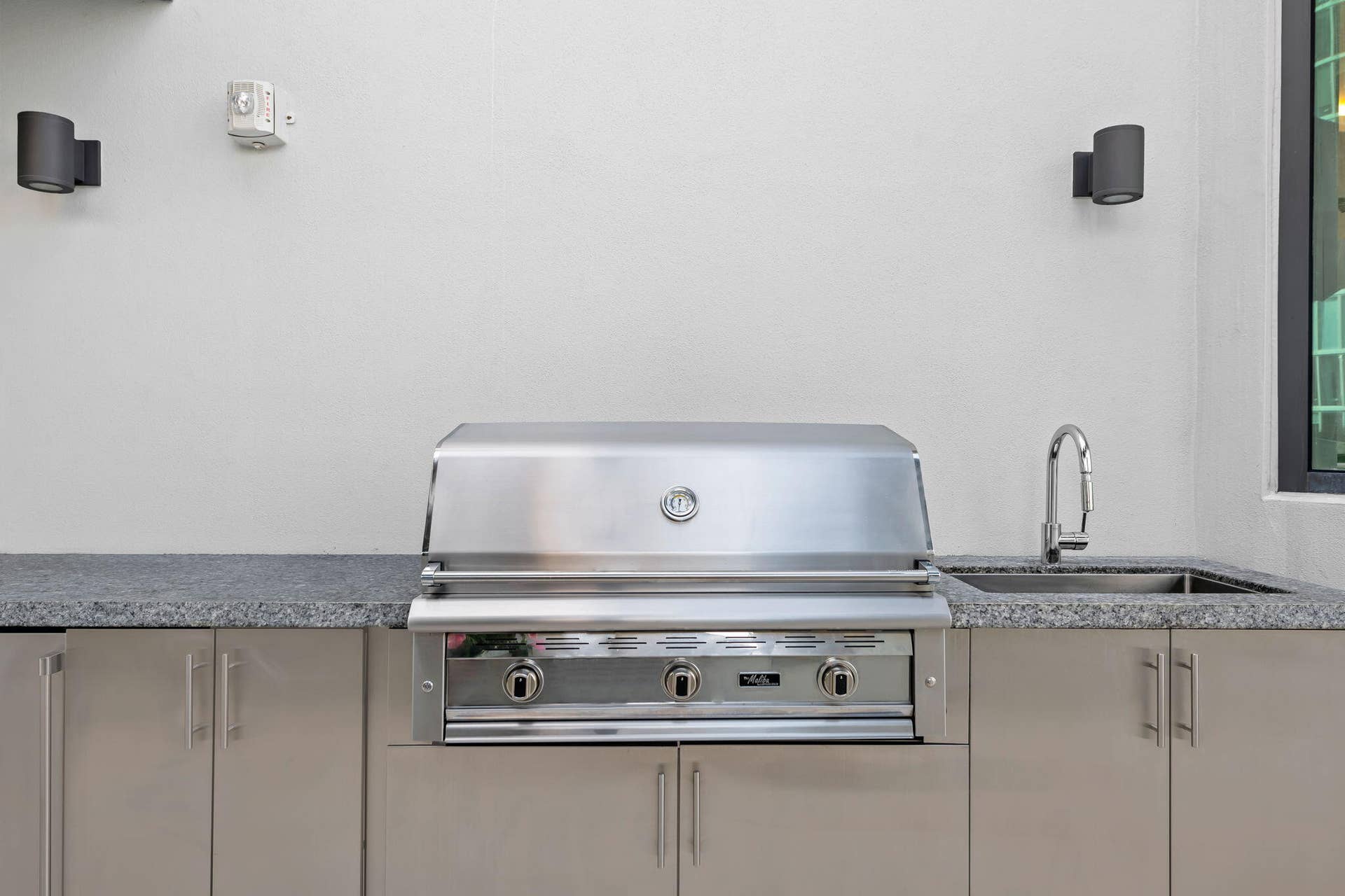 100 E Las Olas Boulevard, #3804, Fort Lauderdale, FL 33301 Outdoor kitchen featuring a built-in stainless steel grill, integrated sink with a gooseneck faucet, granite-finish countertop, and stainless steel cabinetry