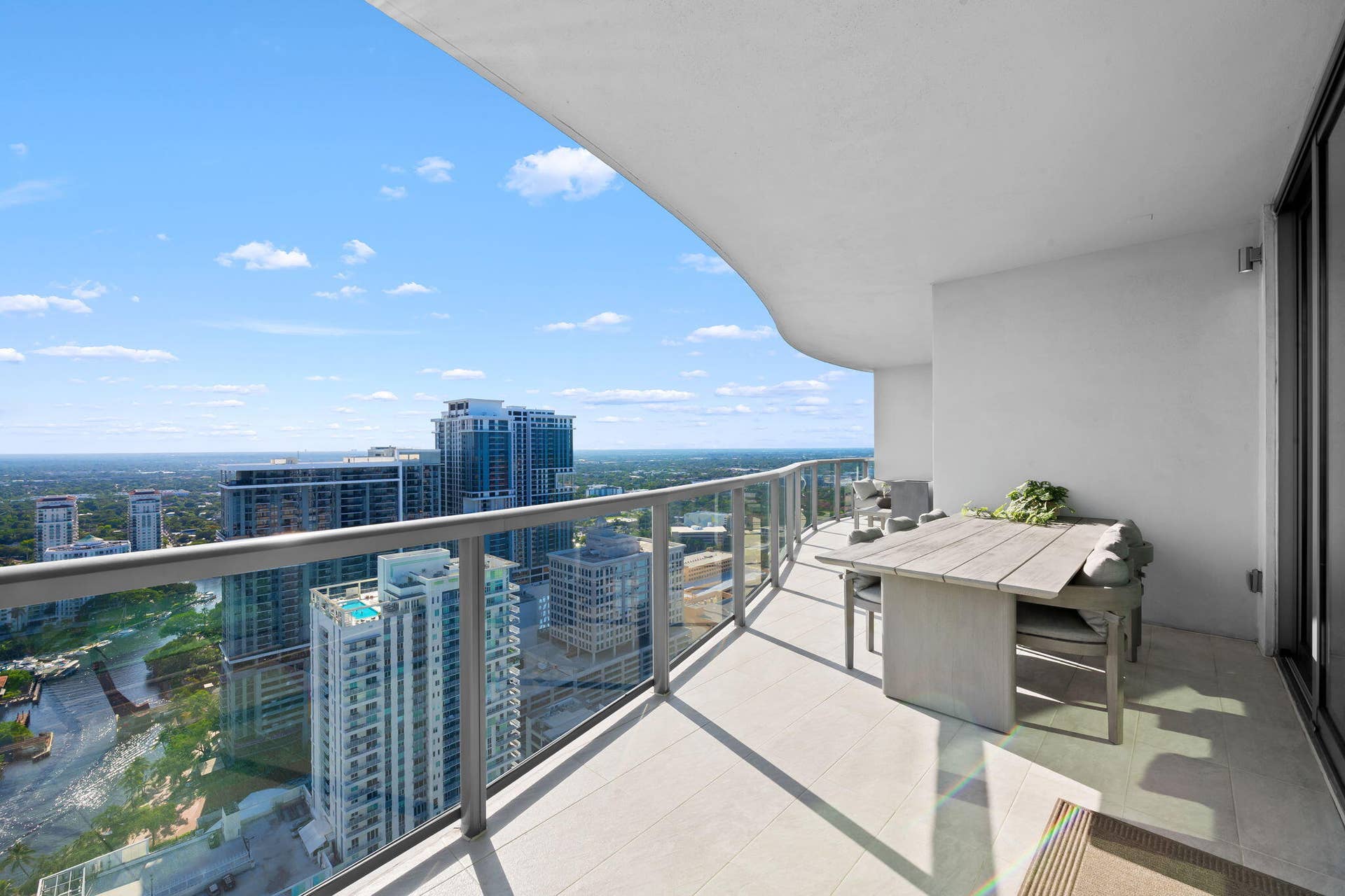 100 E Las Olas Boulevard, #3804, Fort Lauderdale, FL 33301 Expansive curved balcony featuring glass railings, light-toned tile flooring, and a sliding glass door entry