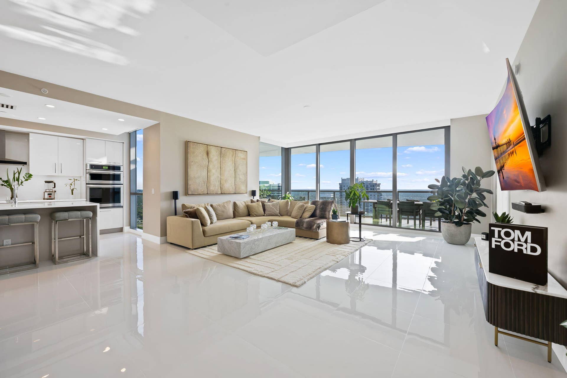 100 E Las Olas Boulevard, #3804, Fort Lauderdale, FL 33301 Open-concept living space featuring high-gloss tile flooring, a contemporary kitchen with white cabinetry and built-in appliances, and expansive floor-to-ceiling windows