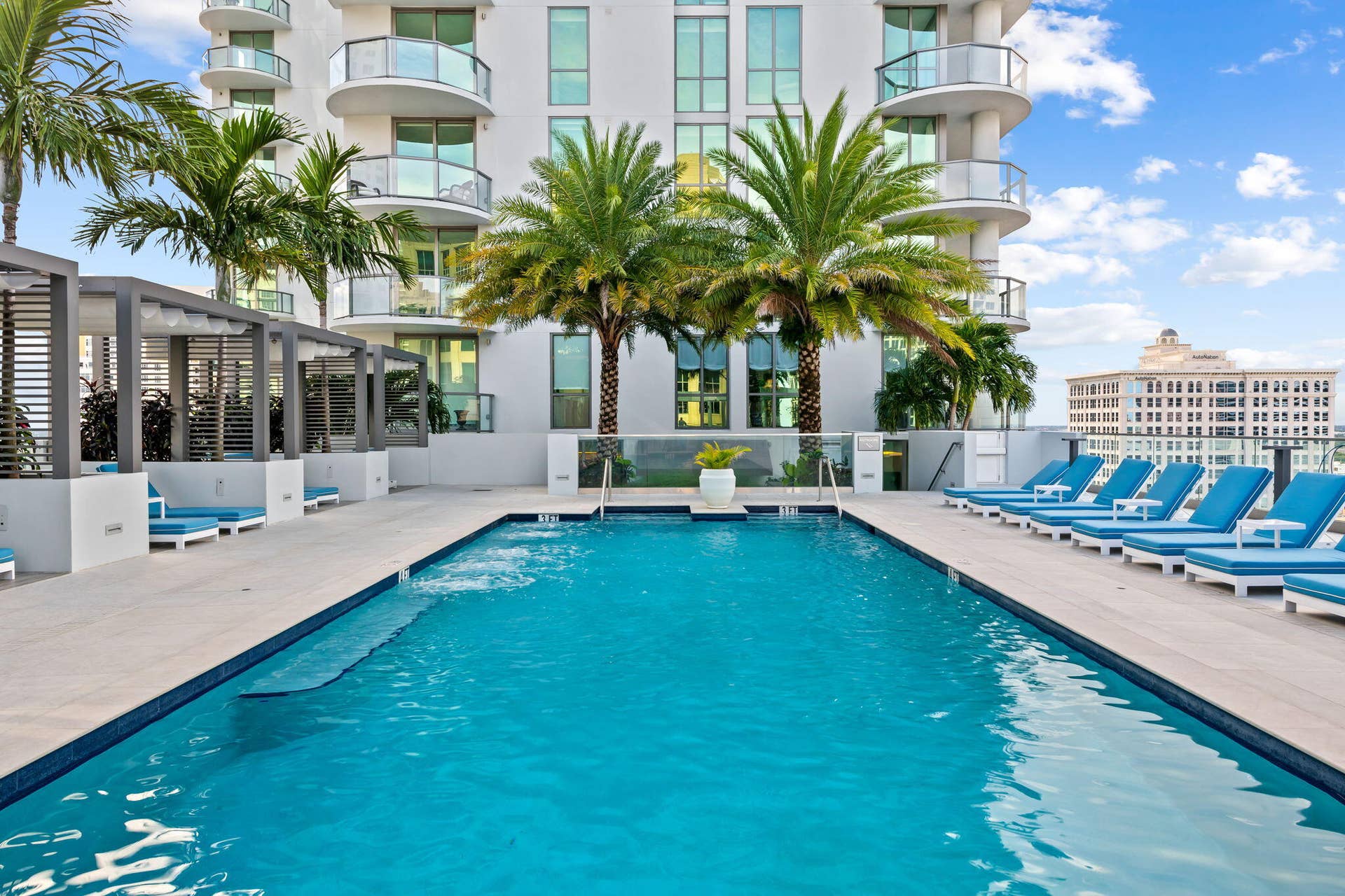 100 E Las Olas Boulevard, #3804, Fort Lauderdale, FL 33301 Rooftop pool deck featuring an in-ground swimming pool, multiple cabanas with slatted pergolas, and a perimeter of tropical palm trees