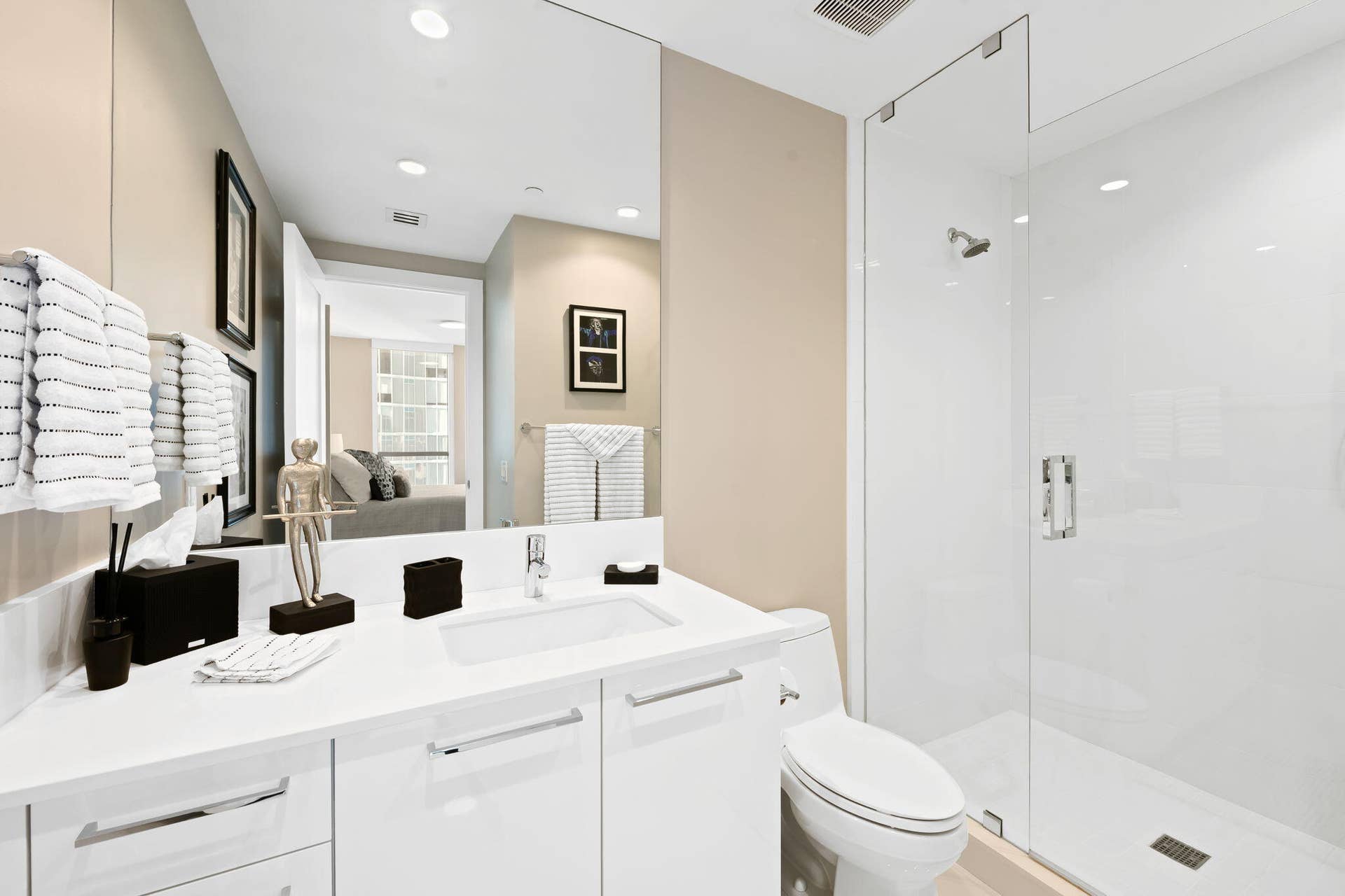 100 E Las Olas Boulevard, #3804, Fort Lauderdale, FL 33301 Modern bathroom featuring a frameless glass shower enclosure, a single vanity with an integrated sink, white cabinetry with chrome hardware, and a large wall-mounted mirror