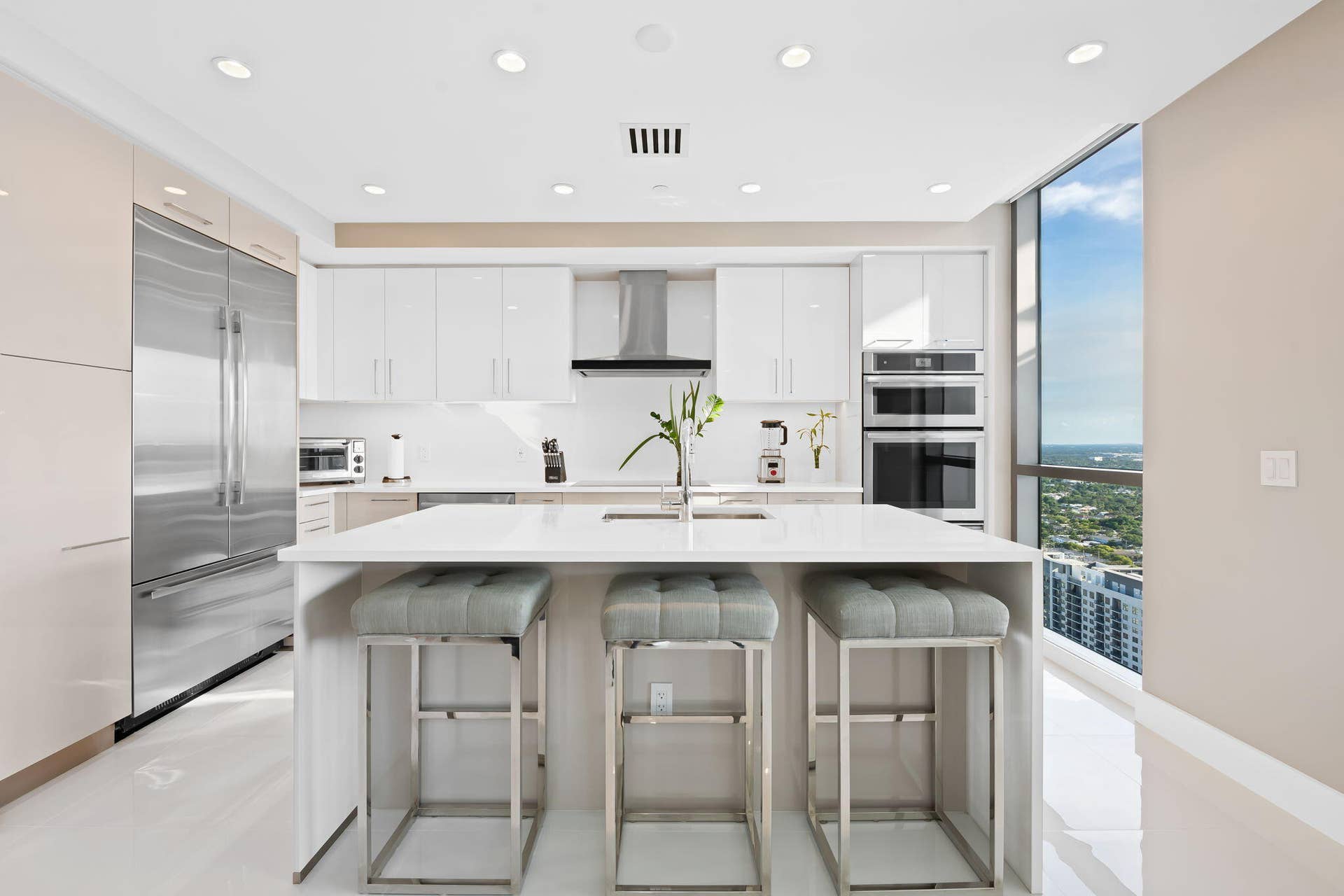100 E Las Olas Boulevard, #3804, Fort Lauderdale, FL 33301 Modern kitchen featuring a large central island with seating, stainless steel appliances, white cabinetry, recessed lighting, and expansive window lines