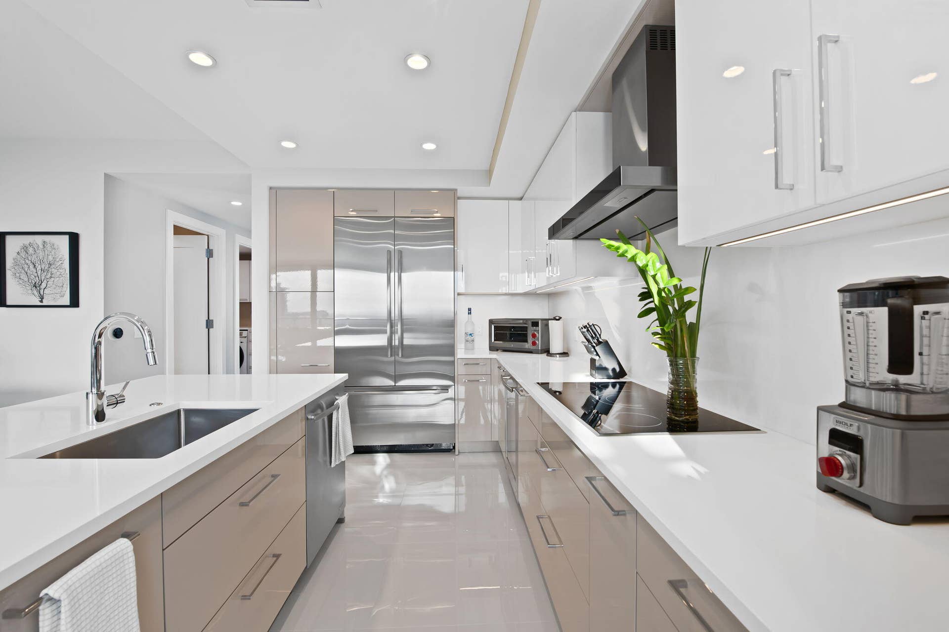 100 E Las Olas Boulevard, #3804, Fort Lauderdale, FL 33301 Sleek kitchen featuring an integrated stainless steel refrigerator, white countertops, and a modern cooktop with an overhead exhaust hood