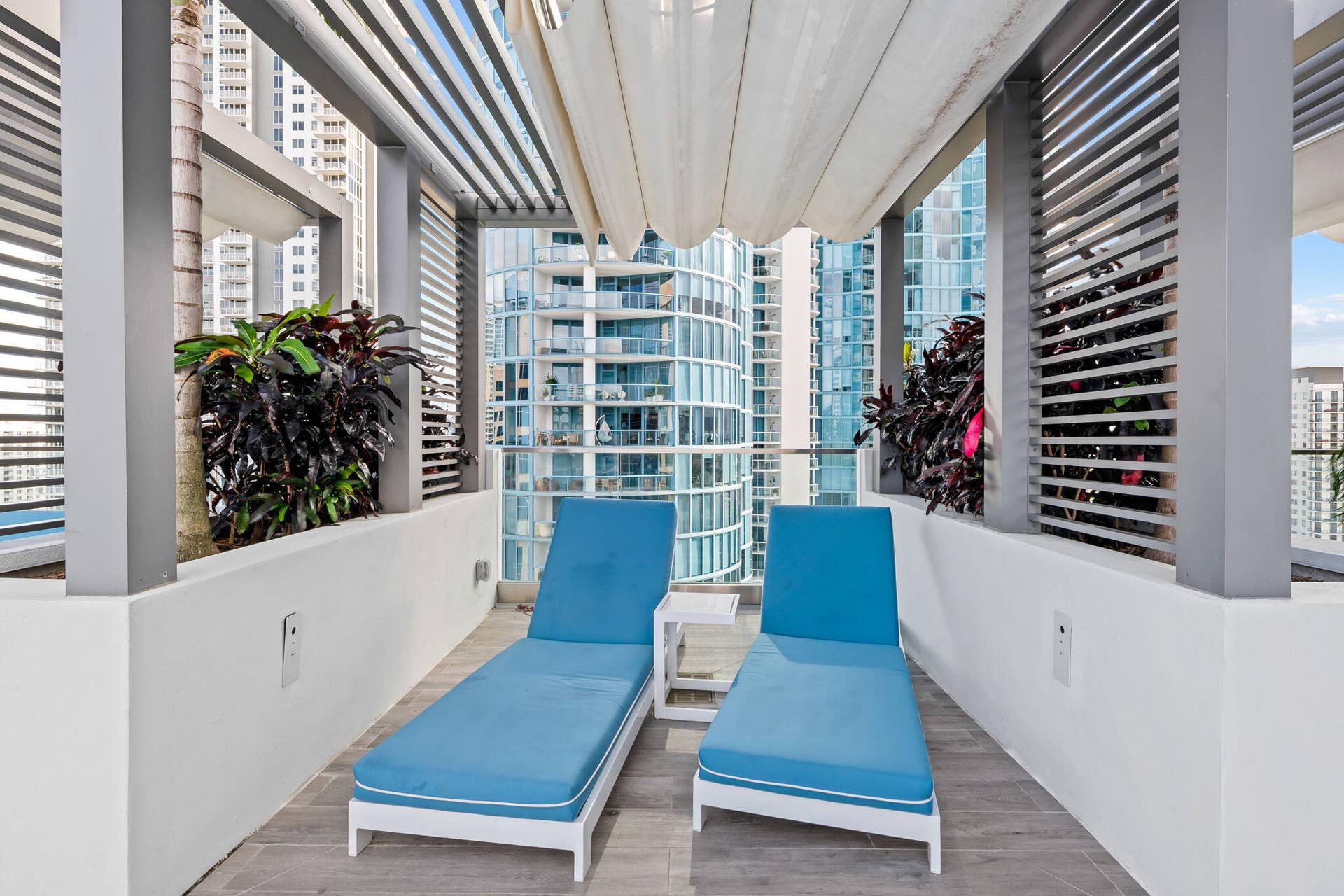 100 E Las Olas Boulevard, #3804, Fort Lauderdale, FL 33301 Outdoor patio area featuring a slatted pergola, retractable overhead canopy, and built-in planters with dense foliage