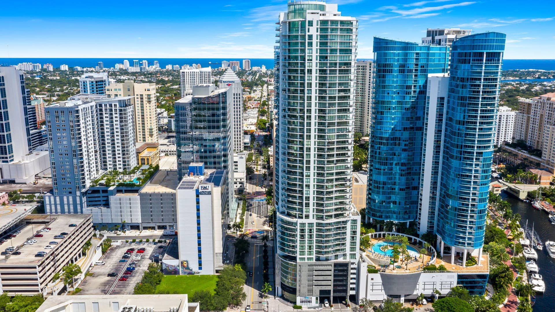 100 E Las Olas Boulevard, #3804, Fort Lauderdale, FL 33301 Modern high-rise architecture featuring blue-tinted glass facades, multiple balconies, a rooftop pool deck, and a canal with docked boats
