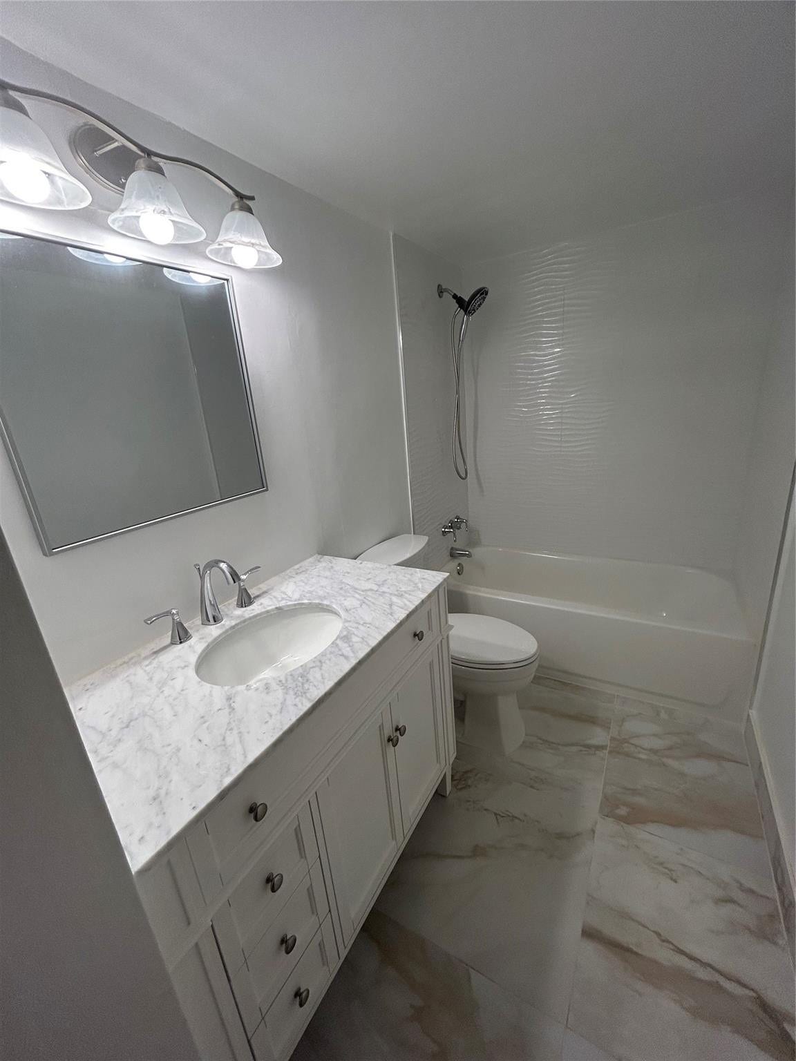 550 Bayshore Drive, #102, Fort Lauderdale, FL 33304 New vanity has marble top and steel faucet and knobs. three draws are vertical and two doors open below the porcelain sink. Mirror above is length of vanity and has a steel frame. New Light fixture has three globe horizontal glass covering connected to a dimmer switch. there is a heat lamp on the ceiling. Bathtub is new with steel facuet and knobs. New Shower hose handle is attached to a hanger with adjustable speeds. New toilet is between the vanity and the tub. Storage closet prehung door.
