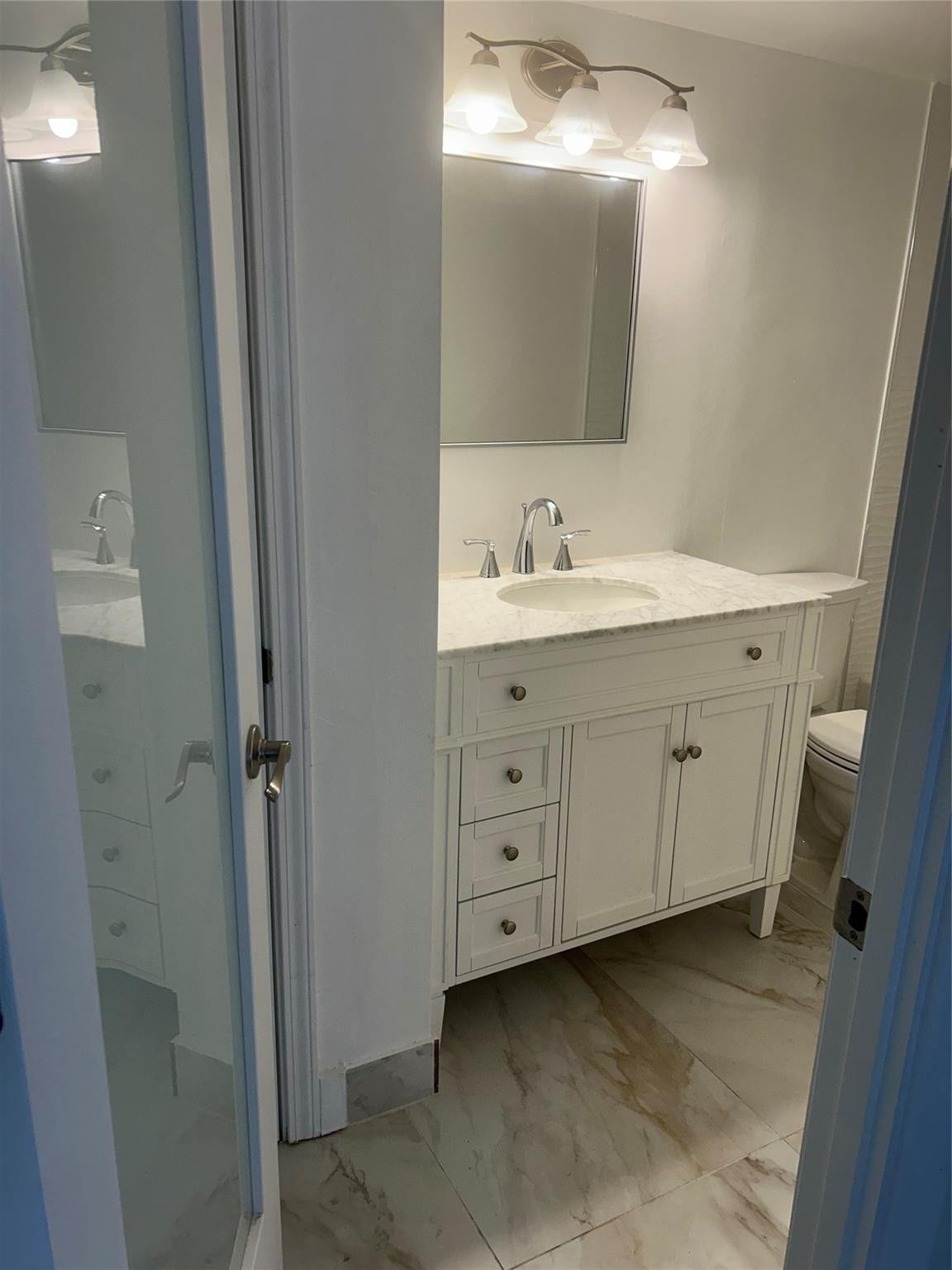 550 Bayshore Drive, #102, Fort Lauderdale, FL 33304 Frosted glass door leads into this bathroom. four shelve storage closet is on the side of the vanity walls with a pre hung door. Ceramic tile flooring and baseboards surround the area.