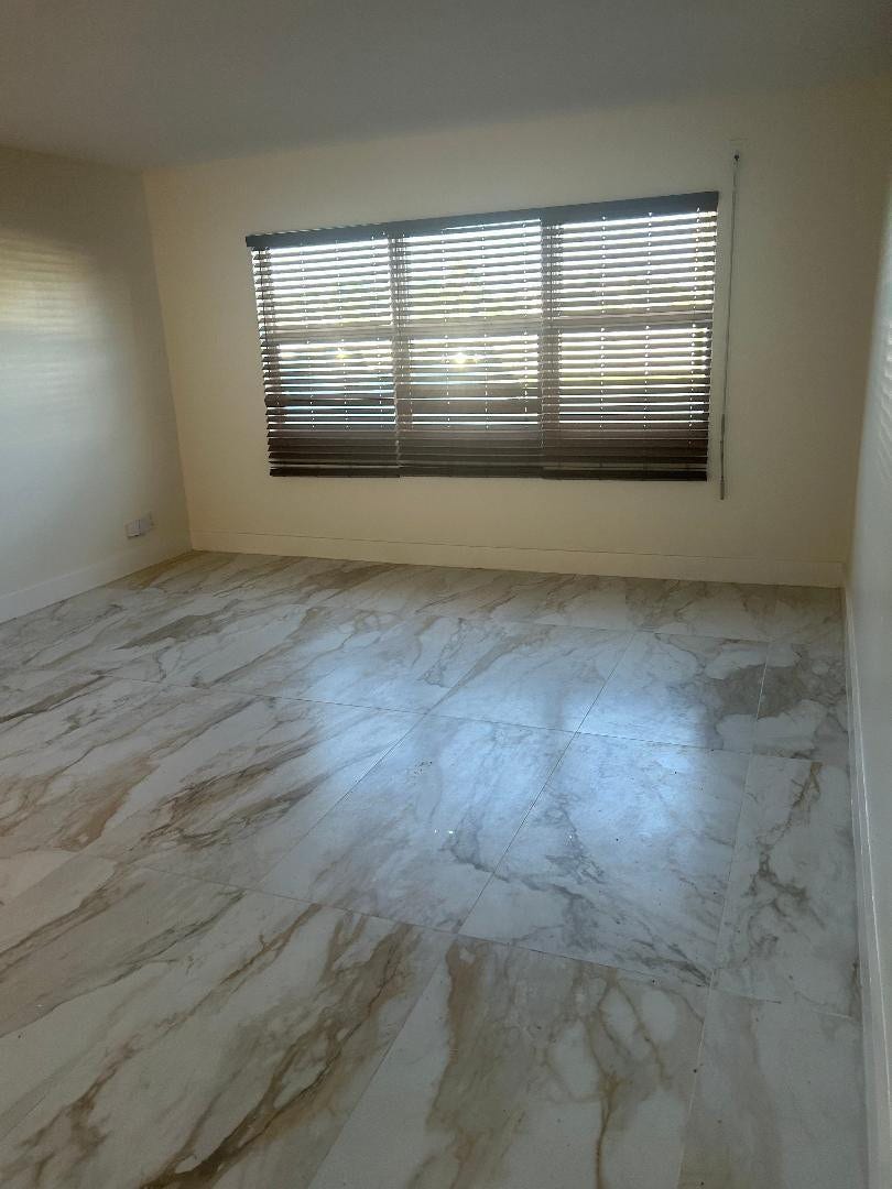550 Bayshore Drive, #102, Fort Lauderdale, FL 33304 window view of ouses n landscape across the intracoastal waterway, boats passing by can be seen over fence around vacant lot.