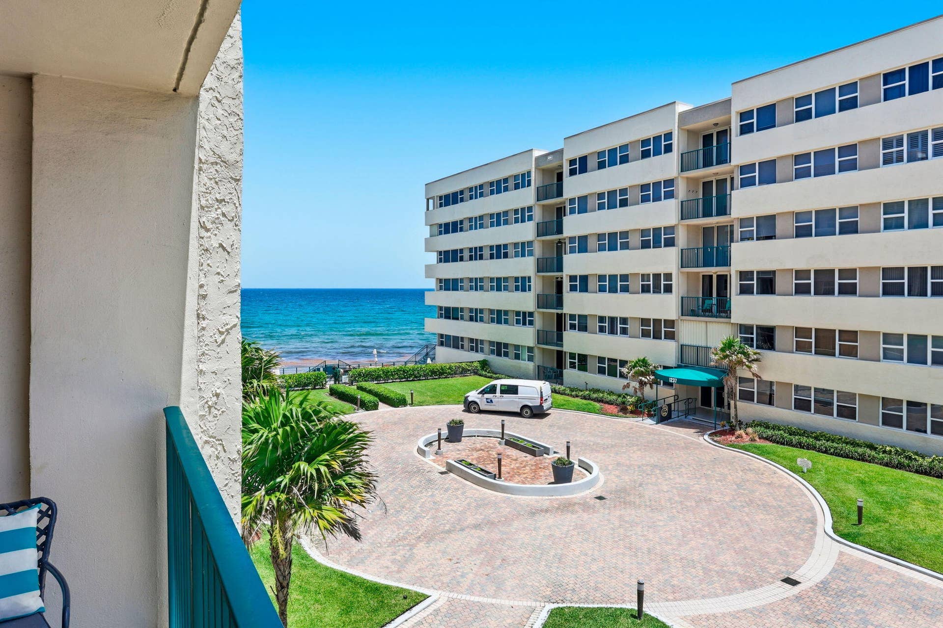 1239 Hillsboro Mile, #302, Hillsboro Beach, FL 33062 Oceanfront building featuring multiple balconies, a circular paver driveway, and a manicured lawn