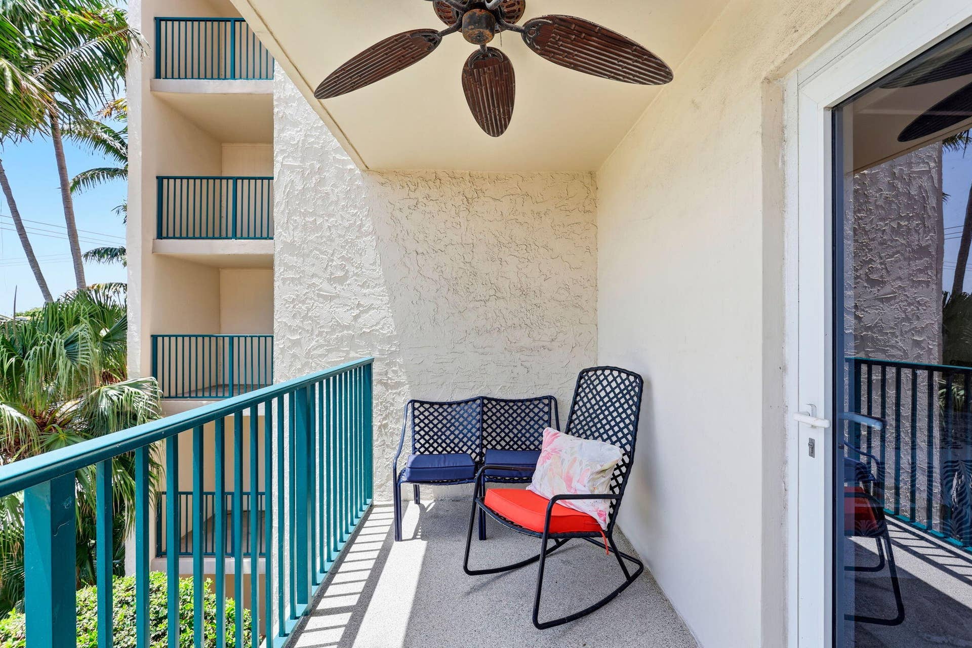 1239 Hillsboro Mile, #302, Hillsboro Beach, FL 33062 Private outdoor balcony featuring a textured stucco finish, a ceiling fan with wood-finish blades, a white sliding glass door, and a teal railing