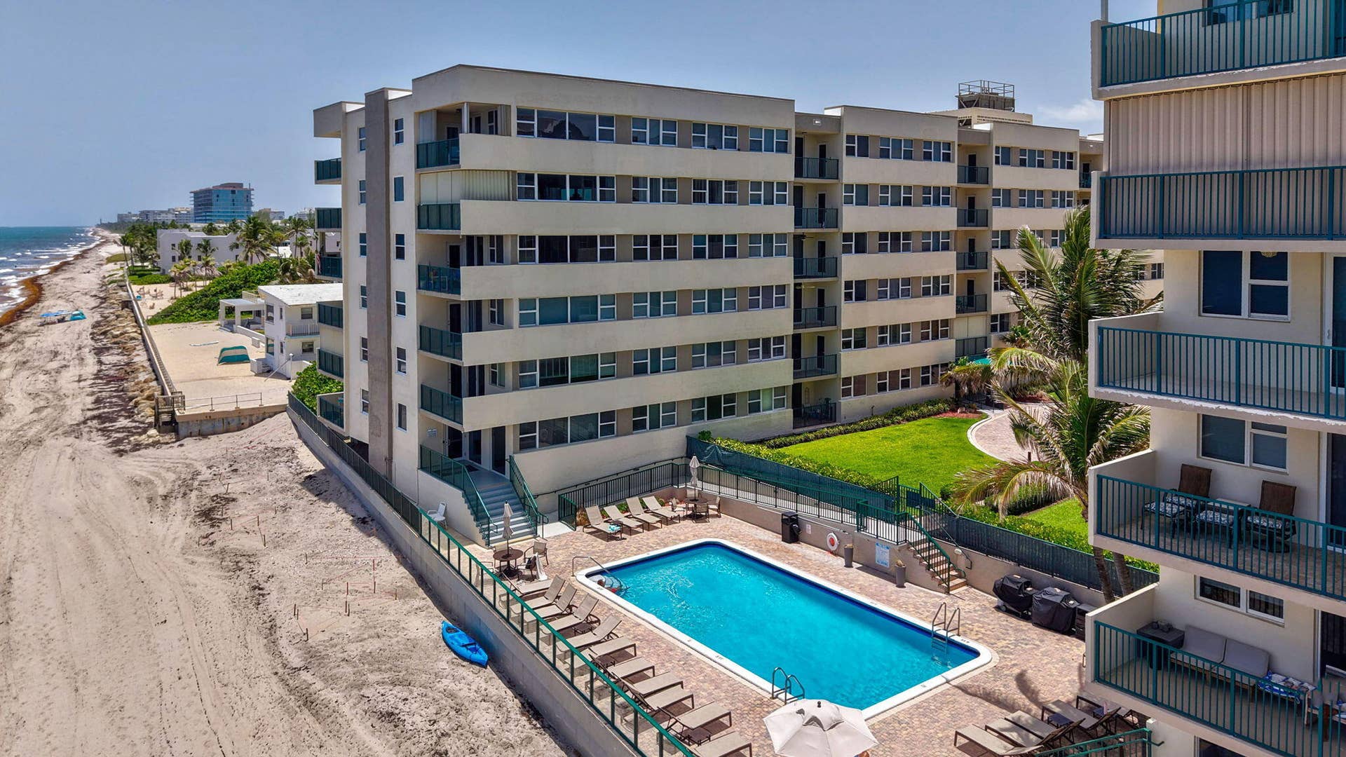 1239 Hillsboro Mile, #302, Hillsboro Beach, FL 33062 Multi-story building featuring private balconies with green railings, an outdoor swimming pool, and a manicured lawn area