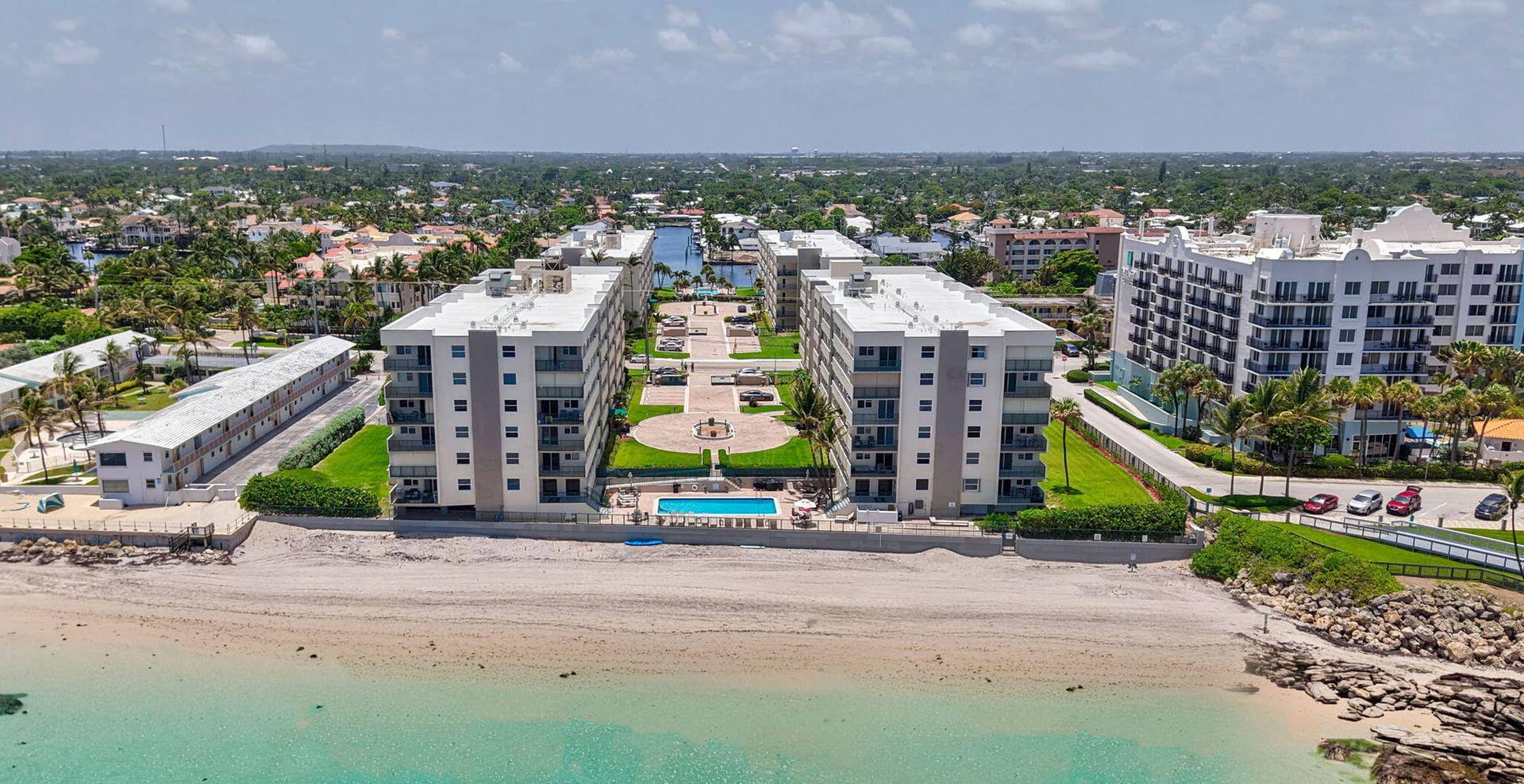 1239 Hillsboro Mile, #302, Hillsboro Beach, FL 33062 Coastal condominium buildings featuring private balconies, a swimming pool, manicured green spaces, and direct beach access