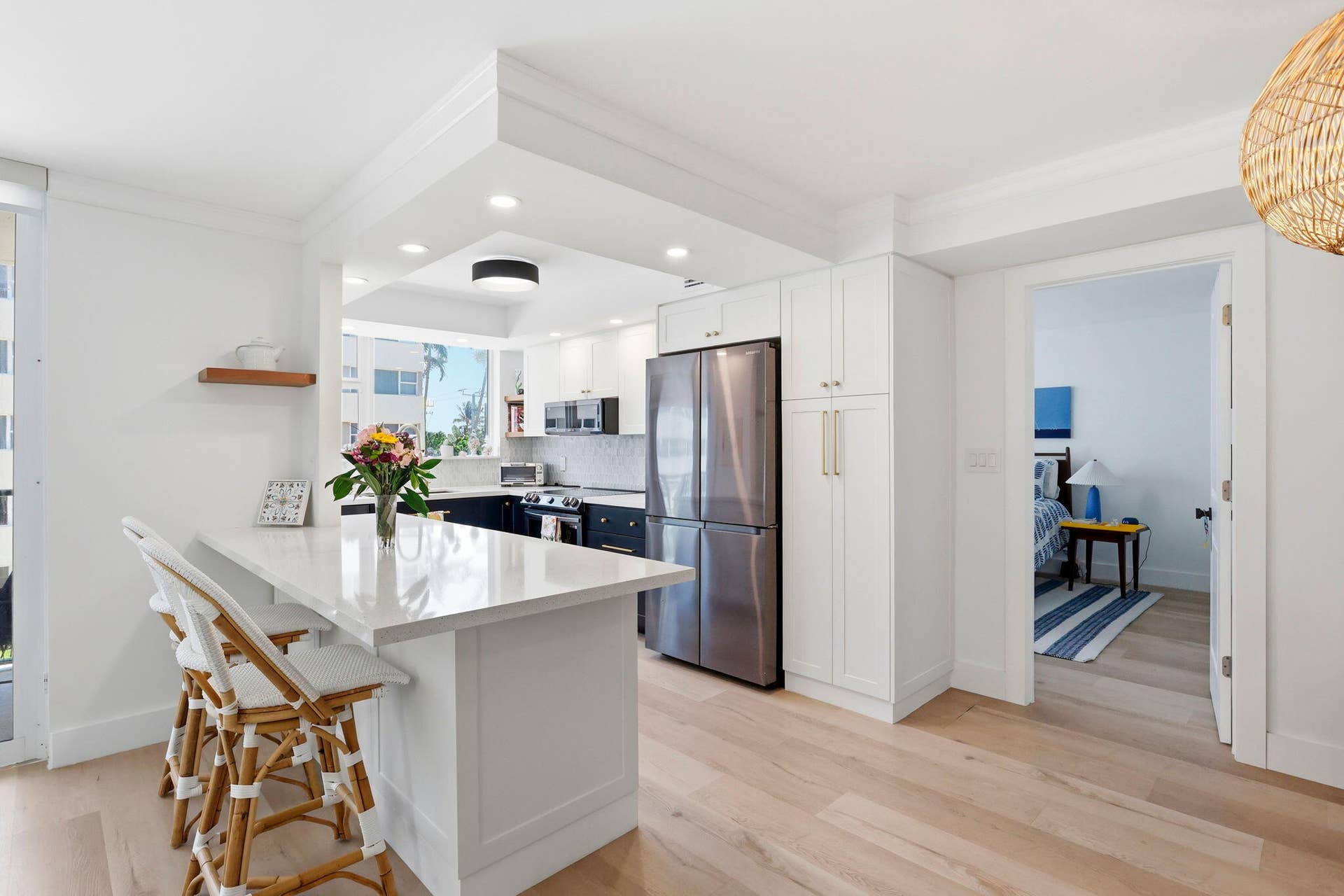 1239 Hillsboro Mile, #302, Hillsboro Beach, FL 33062 Kitchen featuring white shaker cabinetry, stainless steel appliances, light luxury vinyl flooring, and a quartz countertop island with seating