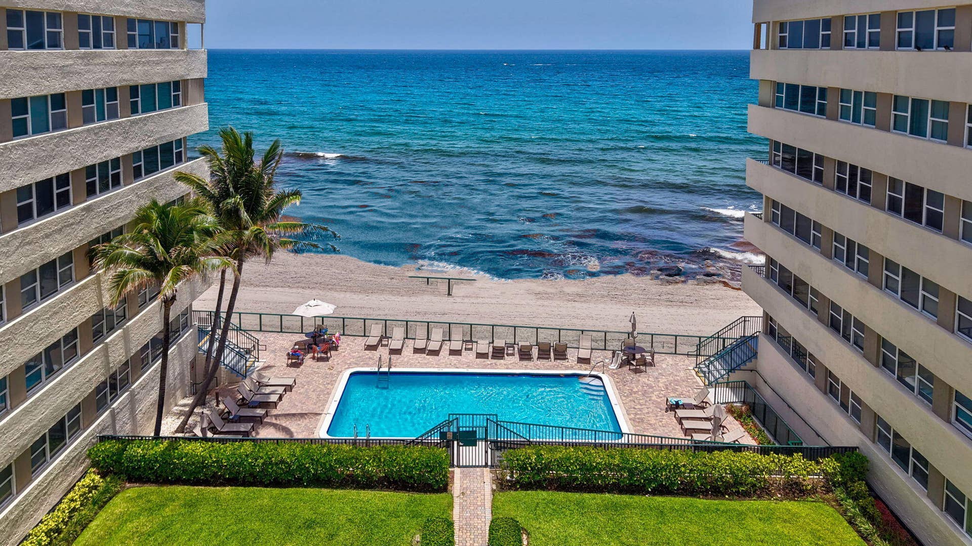 1239 Hillsboro Mile, #302, Hillsboro Beach, FL 33062 Oceanfront building featuring a private swimming pool, direct beach access, and mature palm trees