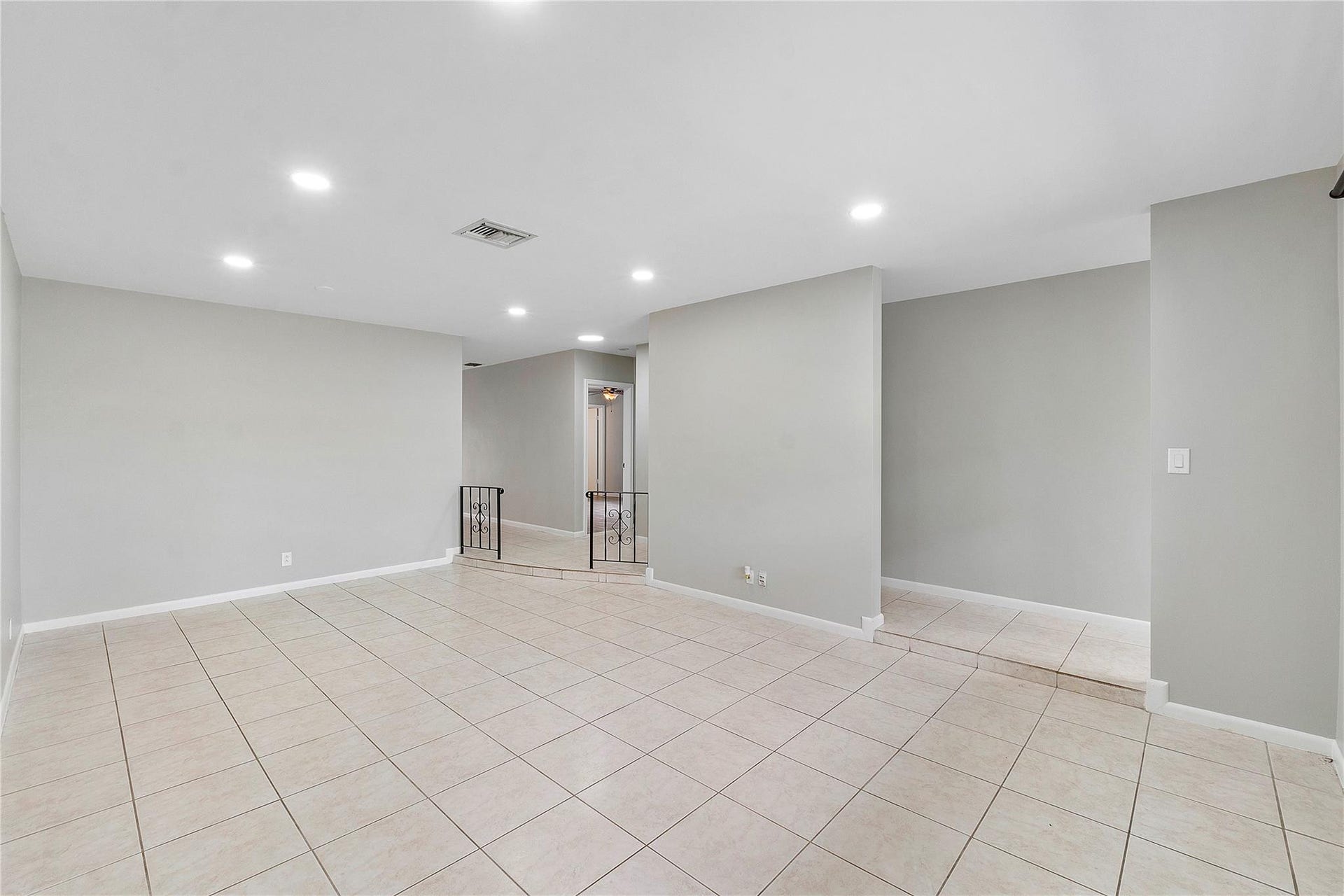 3843 NW 81st Terrace, Coral Springs, Coral Springs, FL 33065 Spacious room featuring tile flooring, neutral wall tones, recessed lighting, and a partial decorative railing