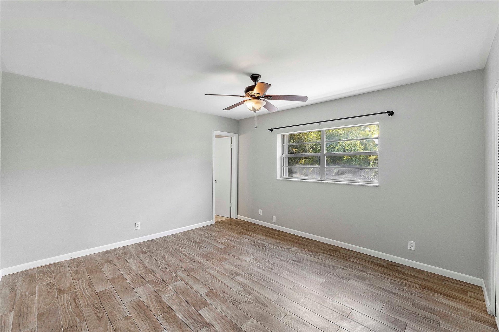 3843 NW 81st Terrace, Coral Springs, Coral Springs, FL 33065 Spacious room featuring light wood-finish flooring, a ceiling fan, a large window, light gray wall paint, and white trim