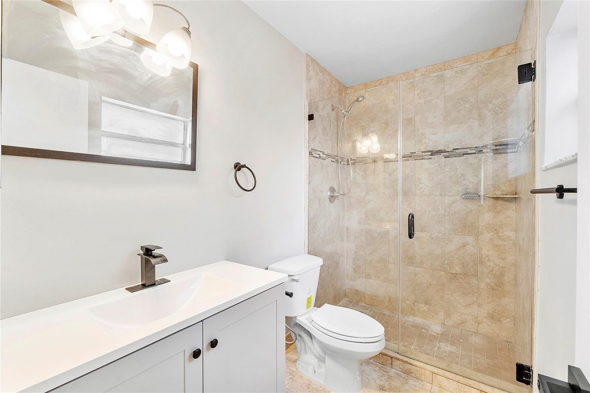 3843 NW 81st Terrace, Coral Springs, Coral Springs, FL 33065 Bathroom featuring a clear glass shower enclosure with tiled walls and an accent band