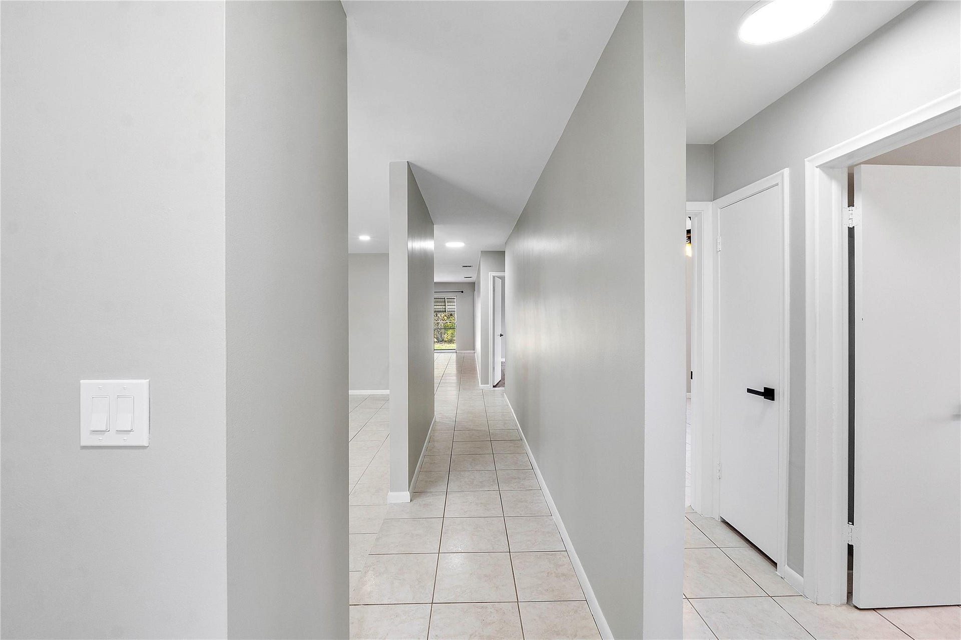 3843 NW 81st Terrace, Coral Springs, Coral Springs, FL 33065 Hallway featuring neutral-toned walls, tile flooring, recessed lighting, and white interior doors with contemporary black hardware
