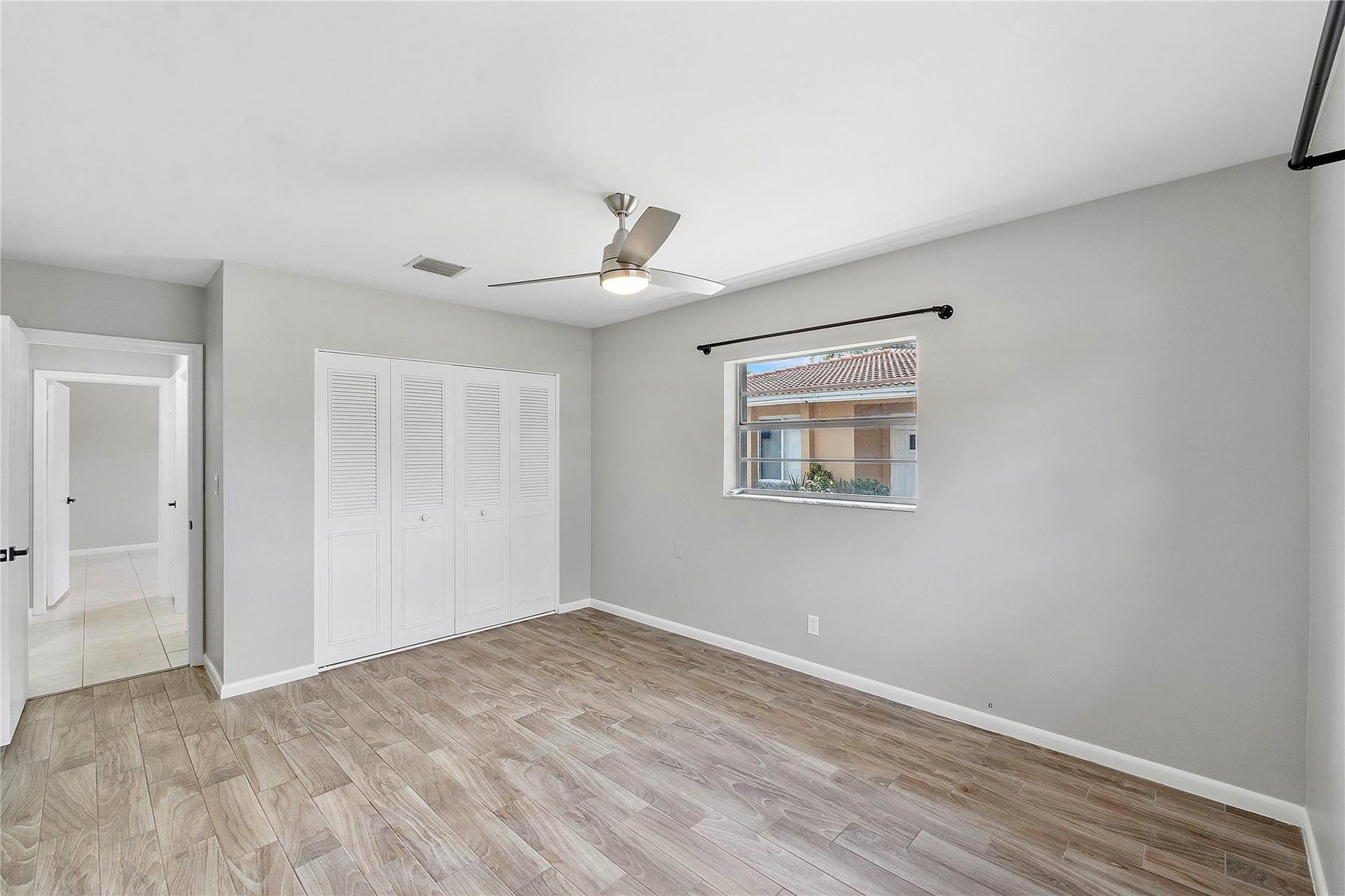 3843 NW 81st Terrace, Coral Springs, Coral Springs, FL 33065 Spacious room featuring wood-finish flooring, light grey walls, and a contemporary ceiling fan