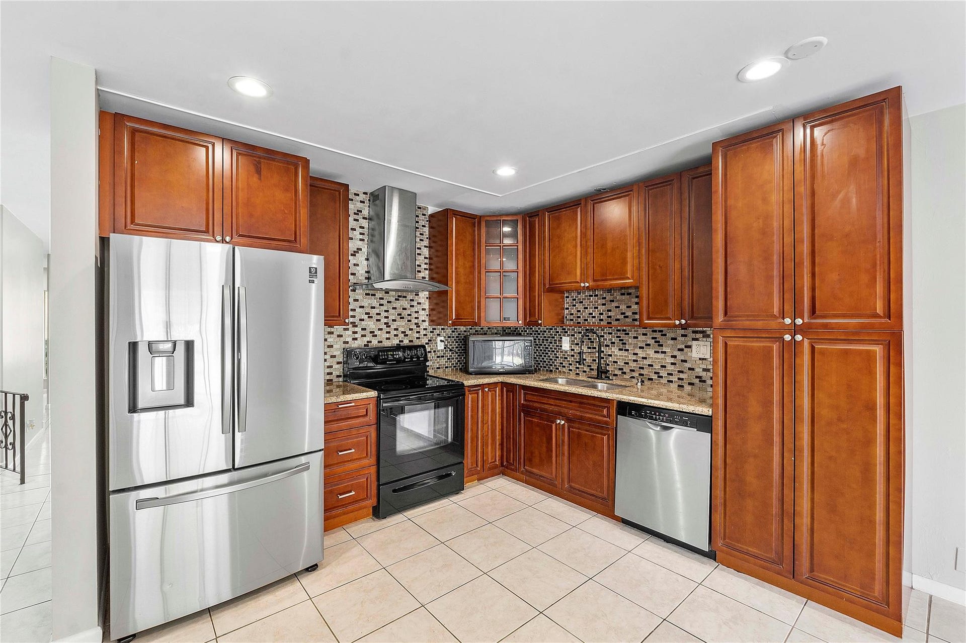 3843 NW 81st Terrace, Coral Springs, Coral Springs, FL 33065 Kitchen featuring wood-finish cabinetry, stainless steel appliances, mosaic tile backsplash, stone countertops, and recessed lighting