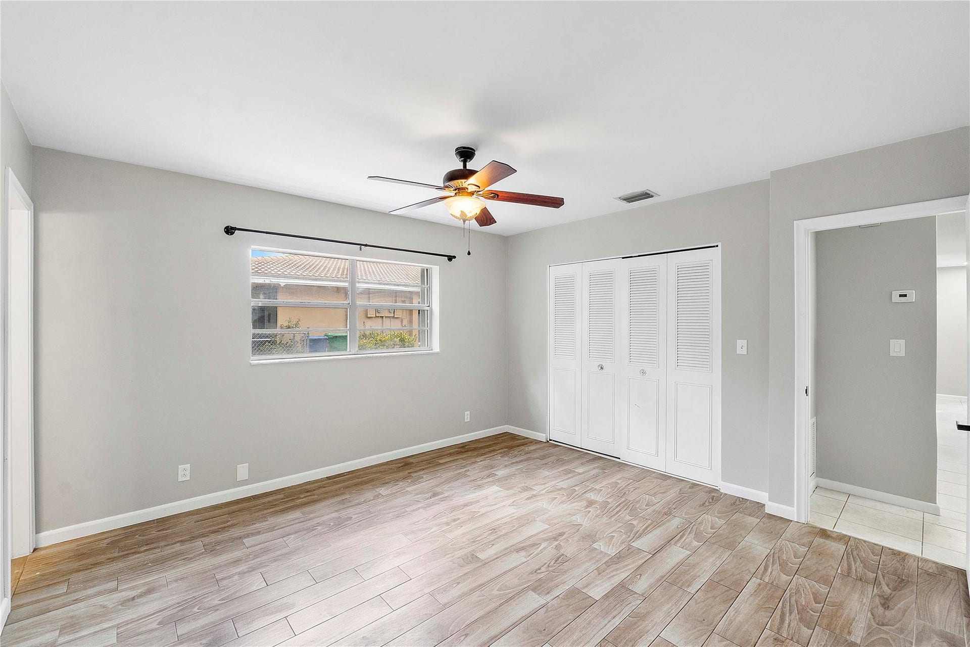 3843 NW 81st Terrace, Coral Springs, Coral Springs, FL 33065 Spacious room with wood-finish flooring, light grey walls, and a ceiling fan with integrated lighting