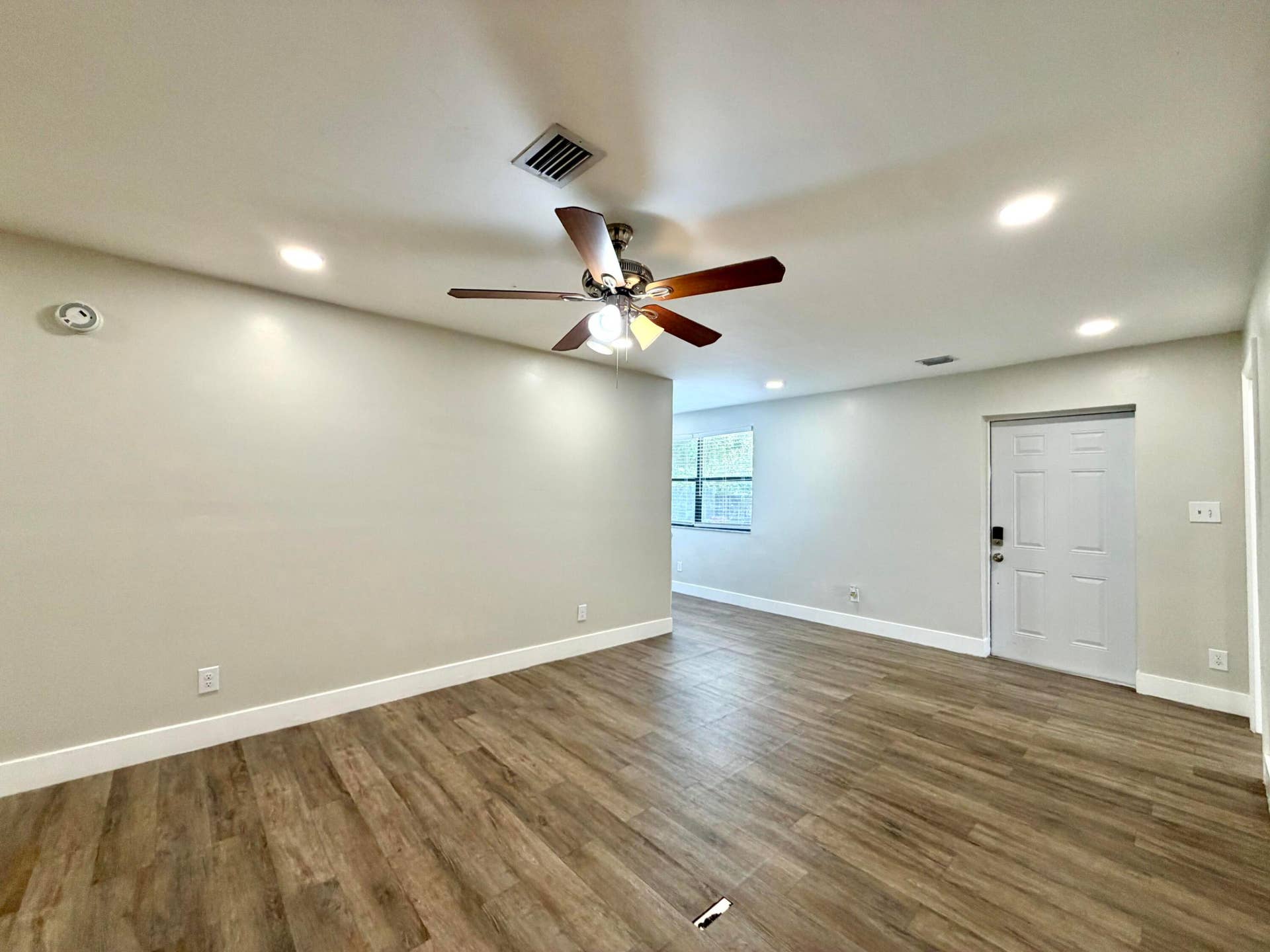 Spacious room featuring wood-style laminate flooring, recessed lighting, and a ceiling fan
