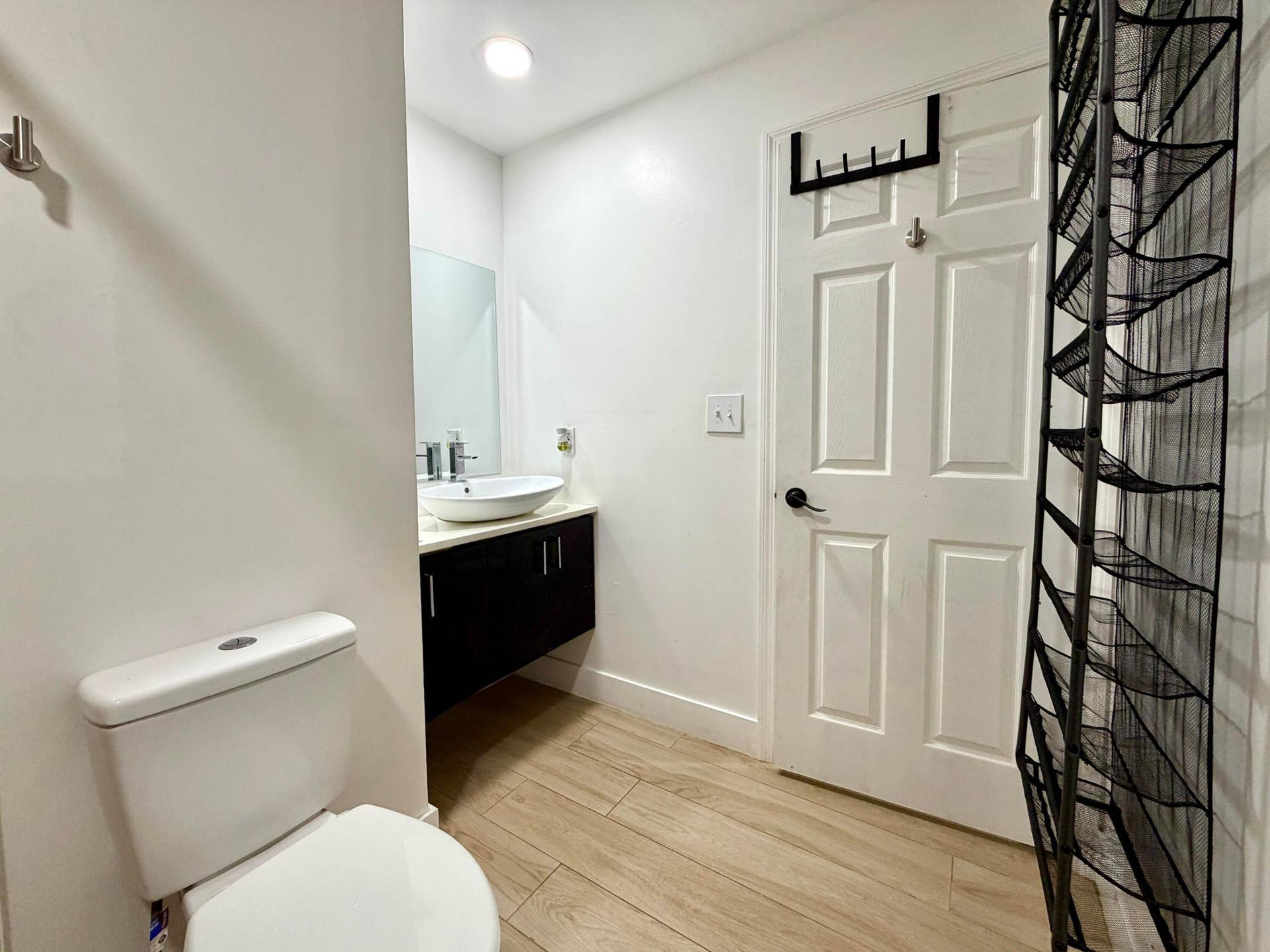 Contemporary bathroom featuring a white vessel sink, dark wood-finish floating vanity, wood look tile flooring, and a white toilet