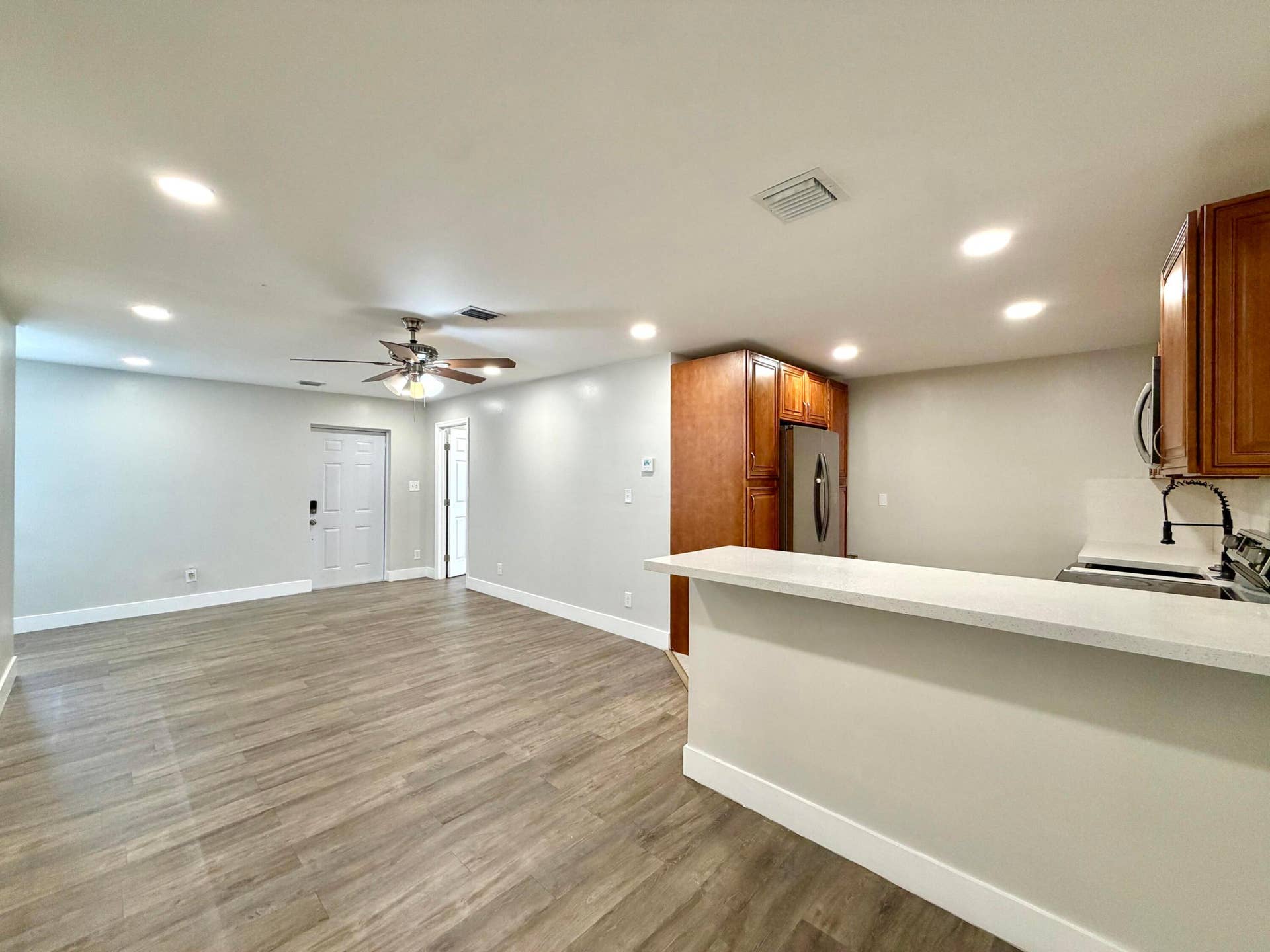 Open-concept living space featuring wood-style laminate flooring, recessed lighting, and a ceiling fan