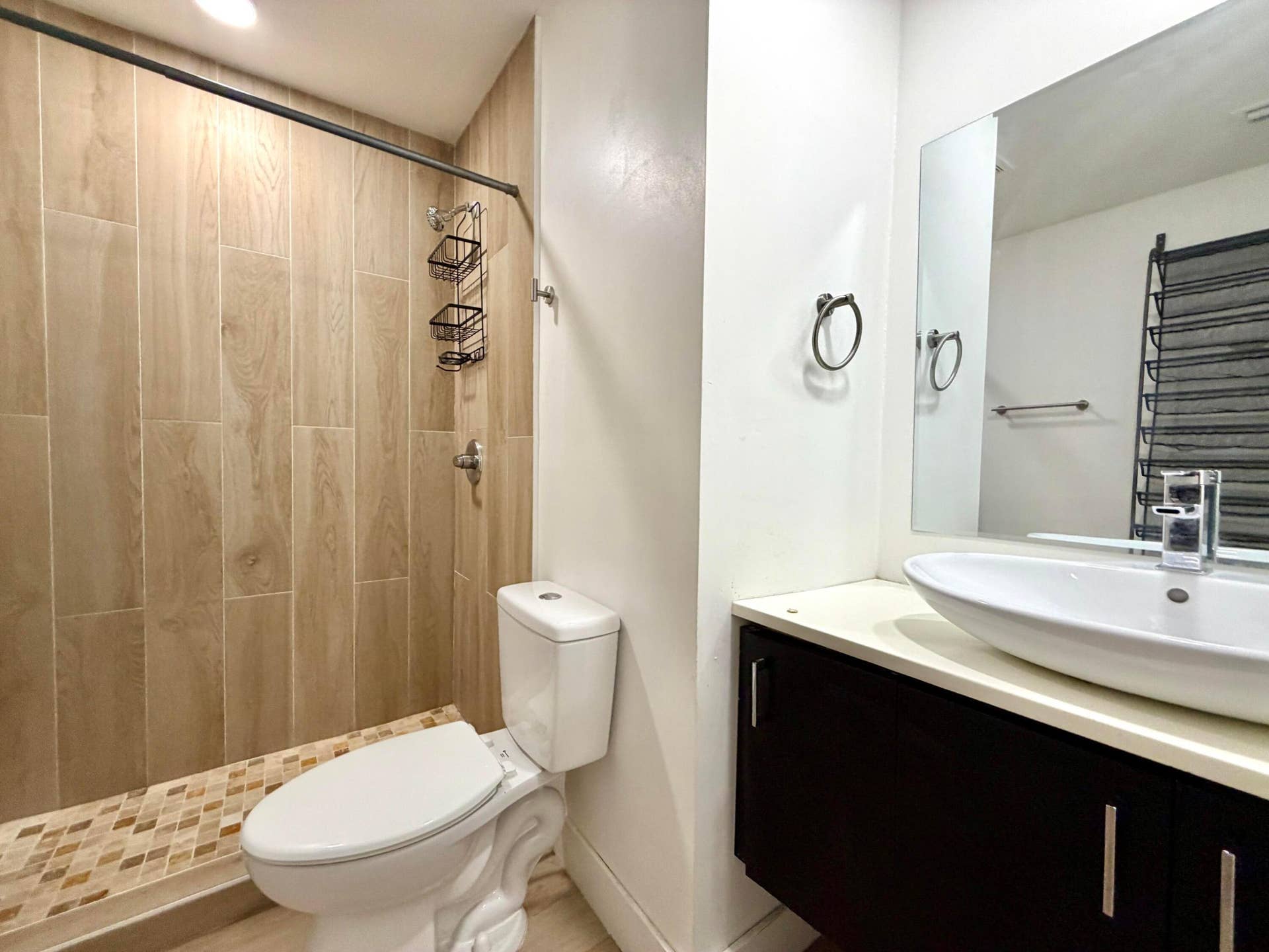 Bathroom featuring a walk-in shower with vertical wood-look tile, mosaic tile shower pan, and a contemporary floating vanity with an oval vessel sink and wall-mounted mirror