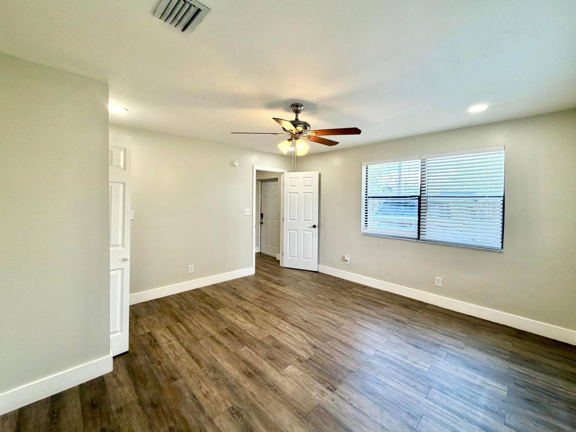 Bedroom 2 featuring wood-style laminate flooring, light-toned walls, a ceiling fan with integrated lighting, a window with horizontal blinds, and white trim throughout