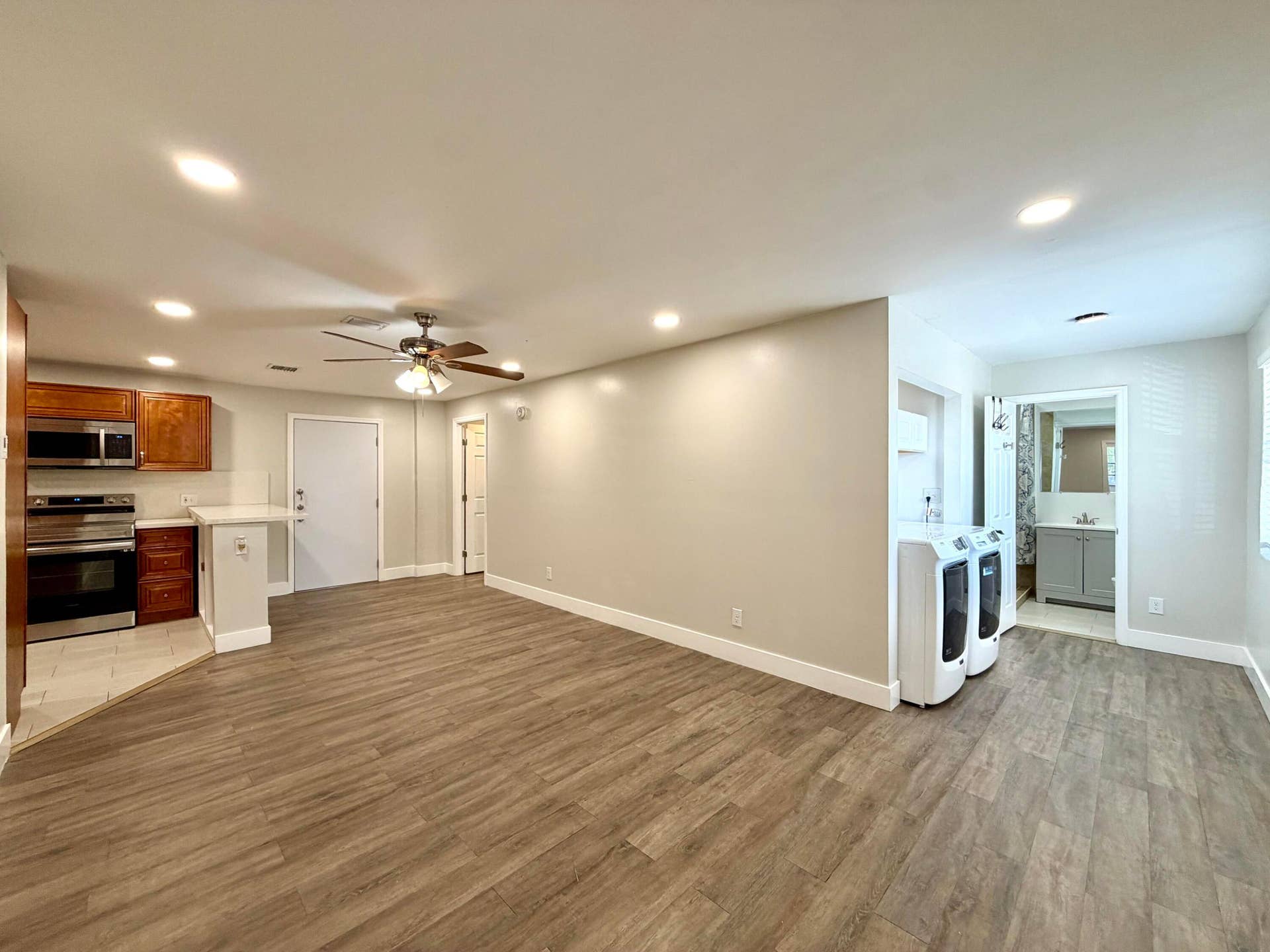 Open-concept living area featuring wood-style laminate flooring, recessed lighting, and a ceiling fan