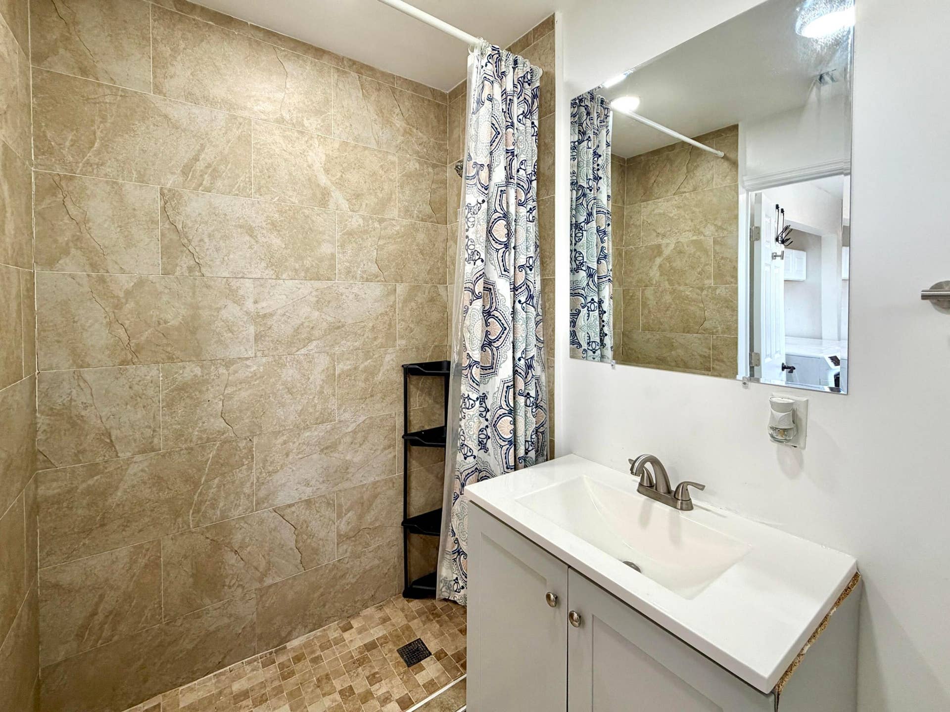 Bathroom featuring a walk-in shower with large format tile surround and mosaic tile flooring