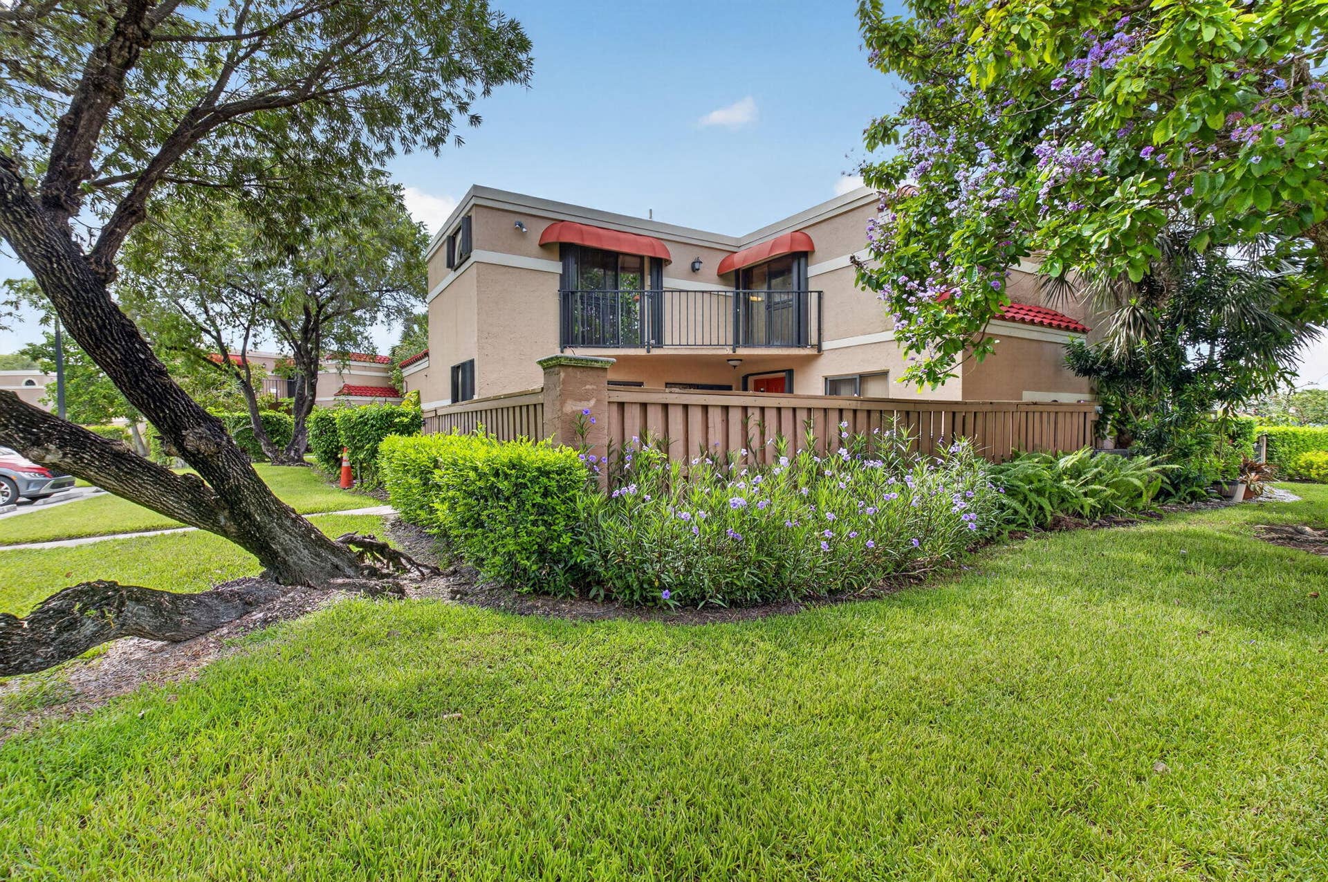 8230 Severn Drive, #A, Boca Raton, FL 33433 Two-story stucco-finish residence featuring a private balcony with black railings and red awnings