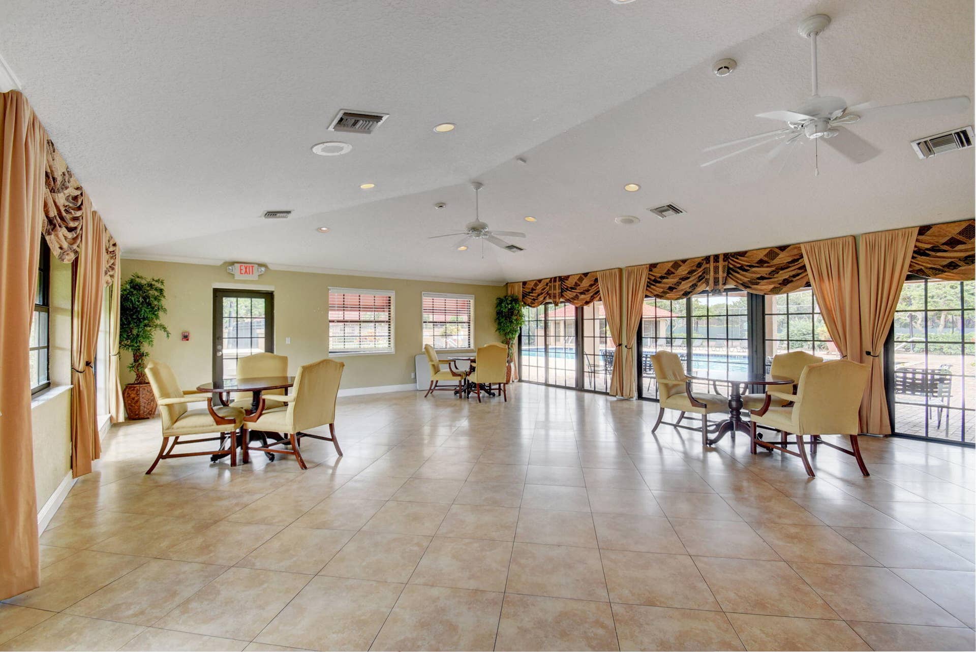 8230 Severn Drive, #A, Boca Raton, FL 33433 Spacious room featuring tile flooring, multiple ceiling fans, recessed lighting, and expansive windows providing outdoor access
