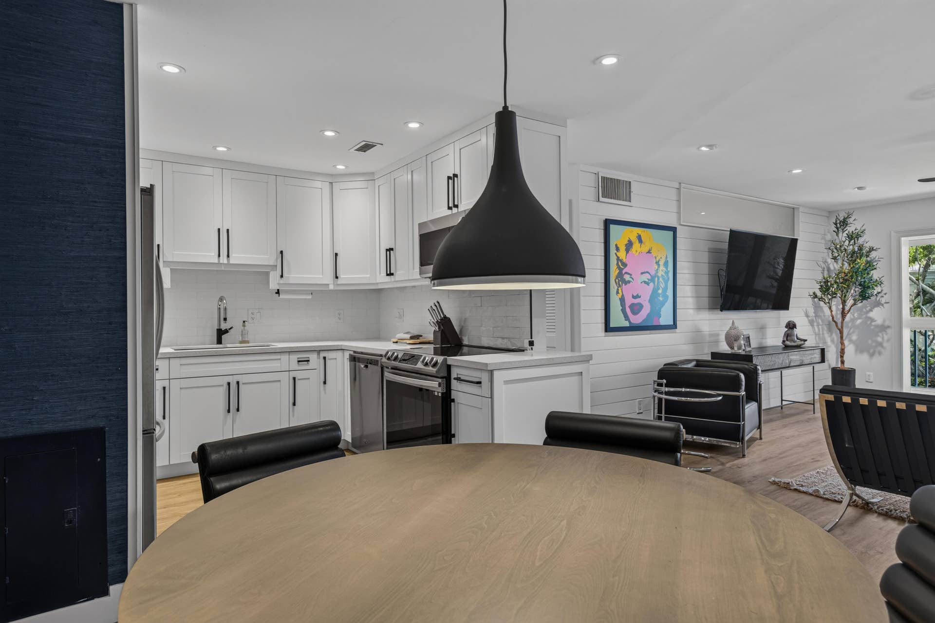 Open-concept kitchen featuring white shaker cabinetry with matte black hardware, stainless steel appliances, white subway tile backsplash, and recessed lighting