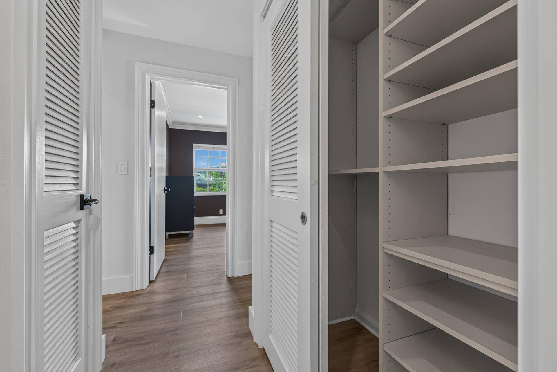 Built-in shelving system featuring adjustable shelves and a louvered bi-fold door