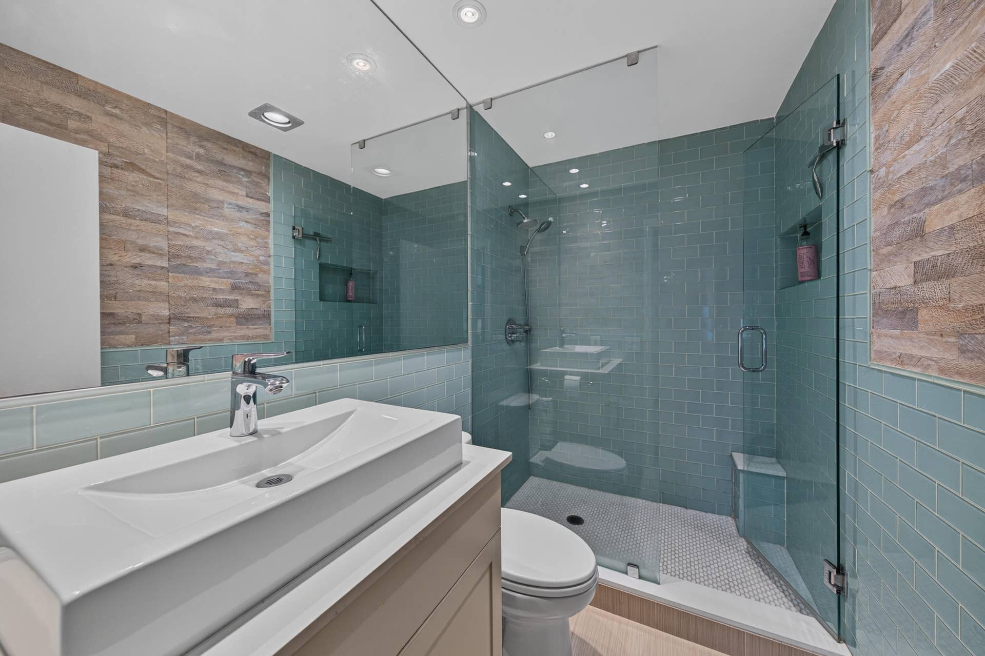 Modern bathroom featuring a glass-enclosed shower with subway tile, an integrated shower bench, and a built-in shower niche