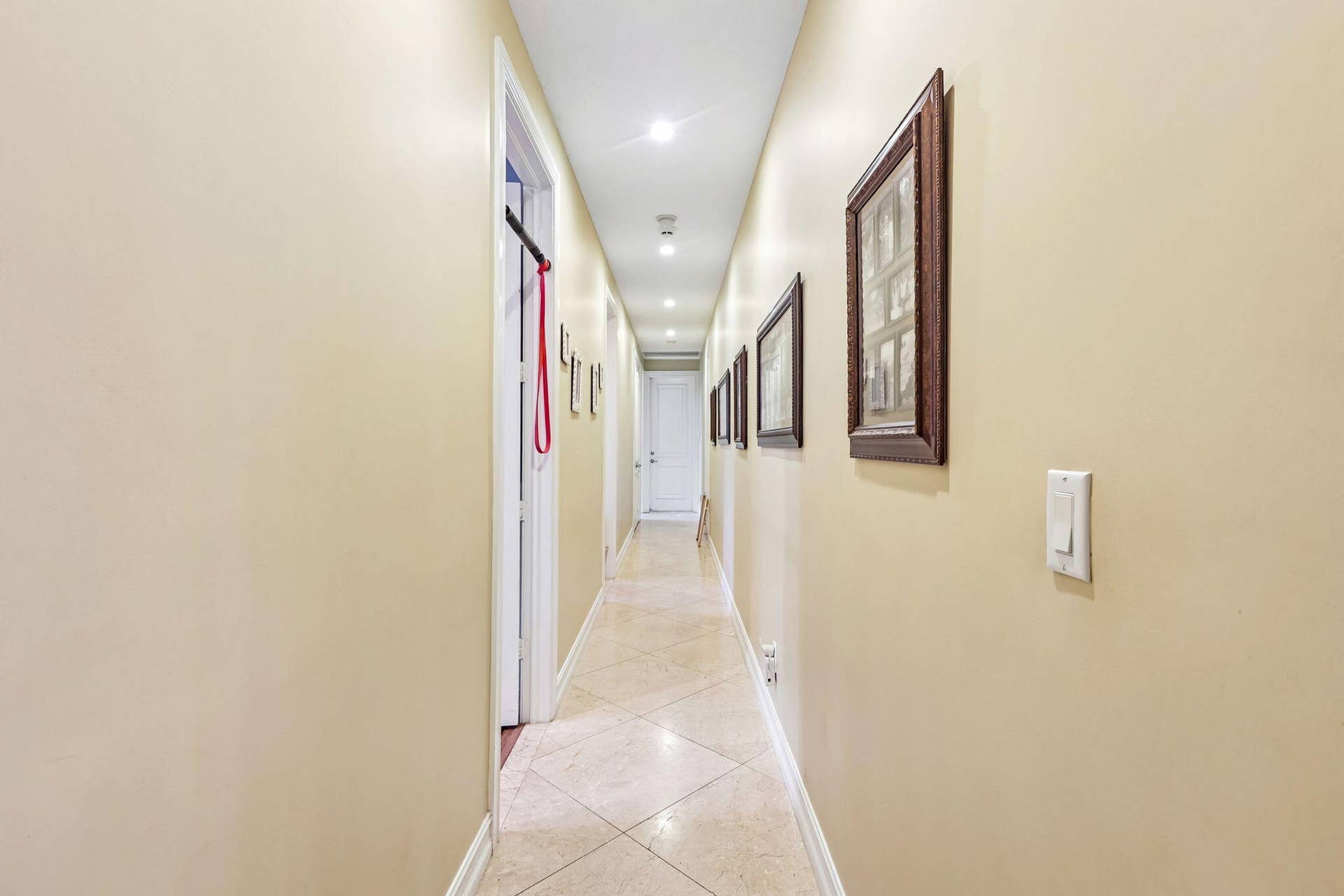 Long hallway featuring recessed lighting and durable tile flooring