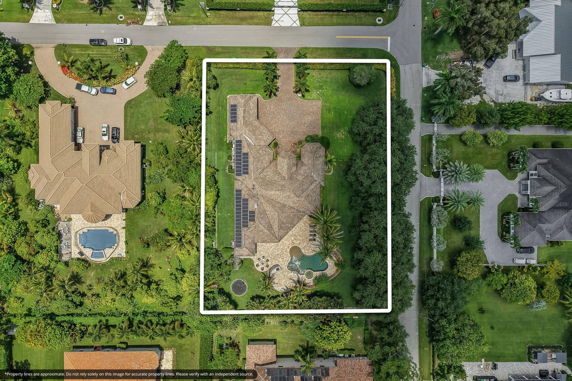 Expansive property featuring a large residence with a multi-gabled tile roof, an integrated swimming pool with a spa, and extensive solar panel installations