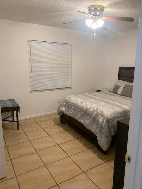 933 Francis Street, West Palm Beach, FL 33405 Room featuring light beige tile flooring, a window with horizontal blinds, and a ceiling fan with integrated lighting